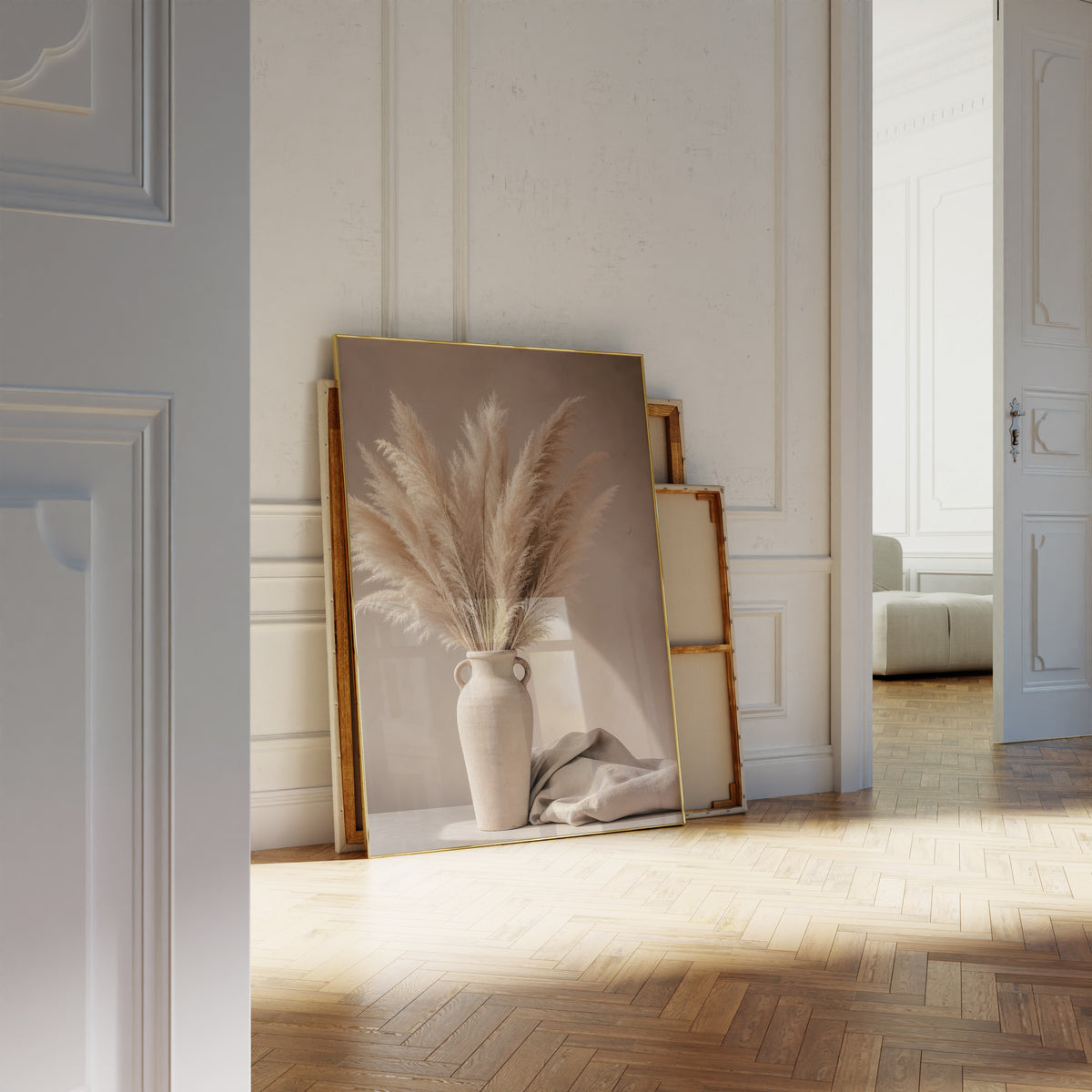 Motiv mit einem Pampasbouquet in einer beigefarbenen Henkelvase neben hellem Stoff, als an die Wand gelehntes Poster neben leeren Rahmen.