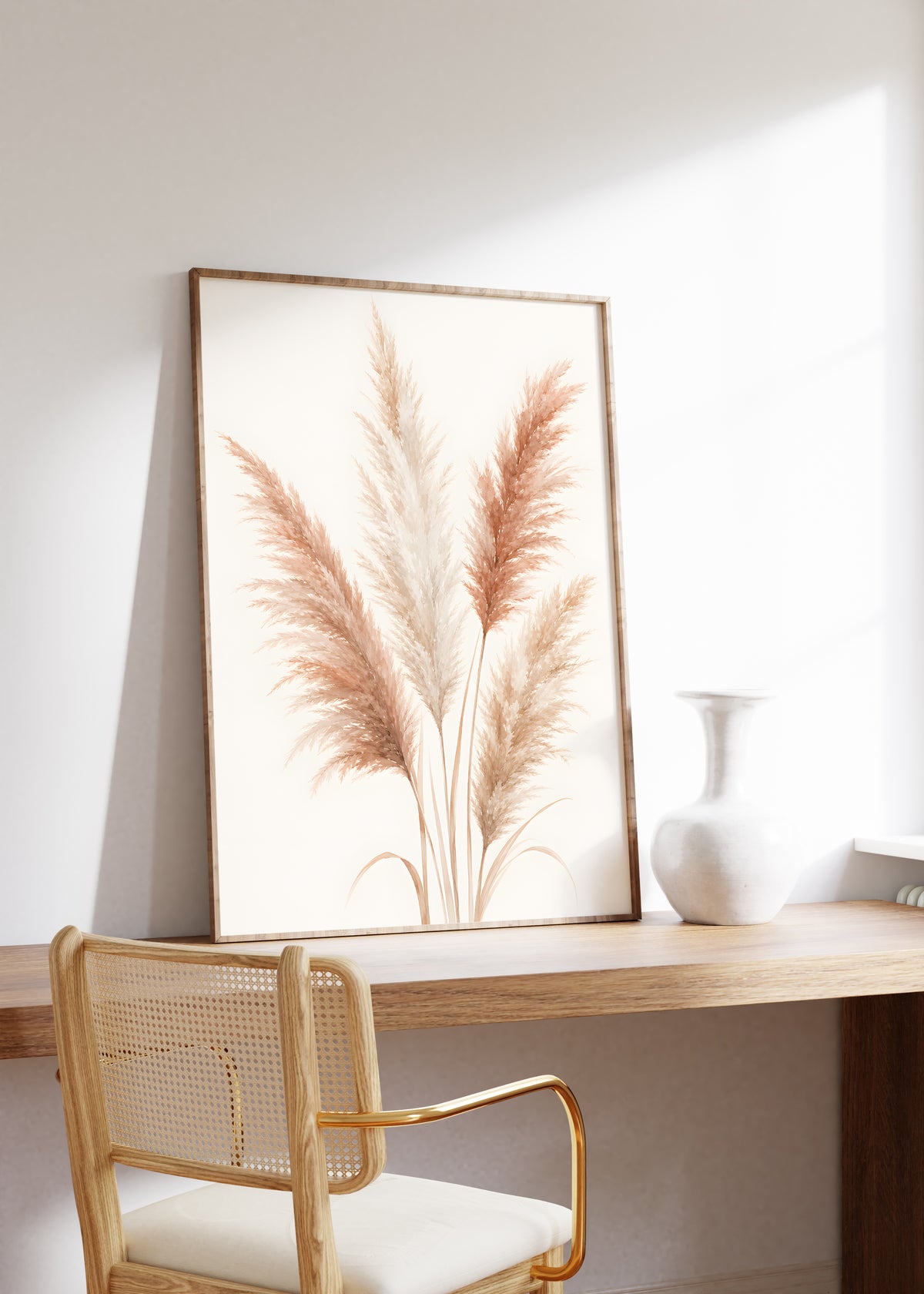 Gerahmtes Poster mit einem illustrierten Pampasbouquet in Rosé und Creme, auf einem Holztisch neben einer weißen Vase.