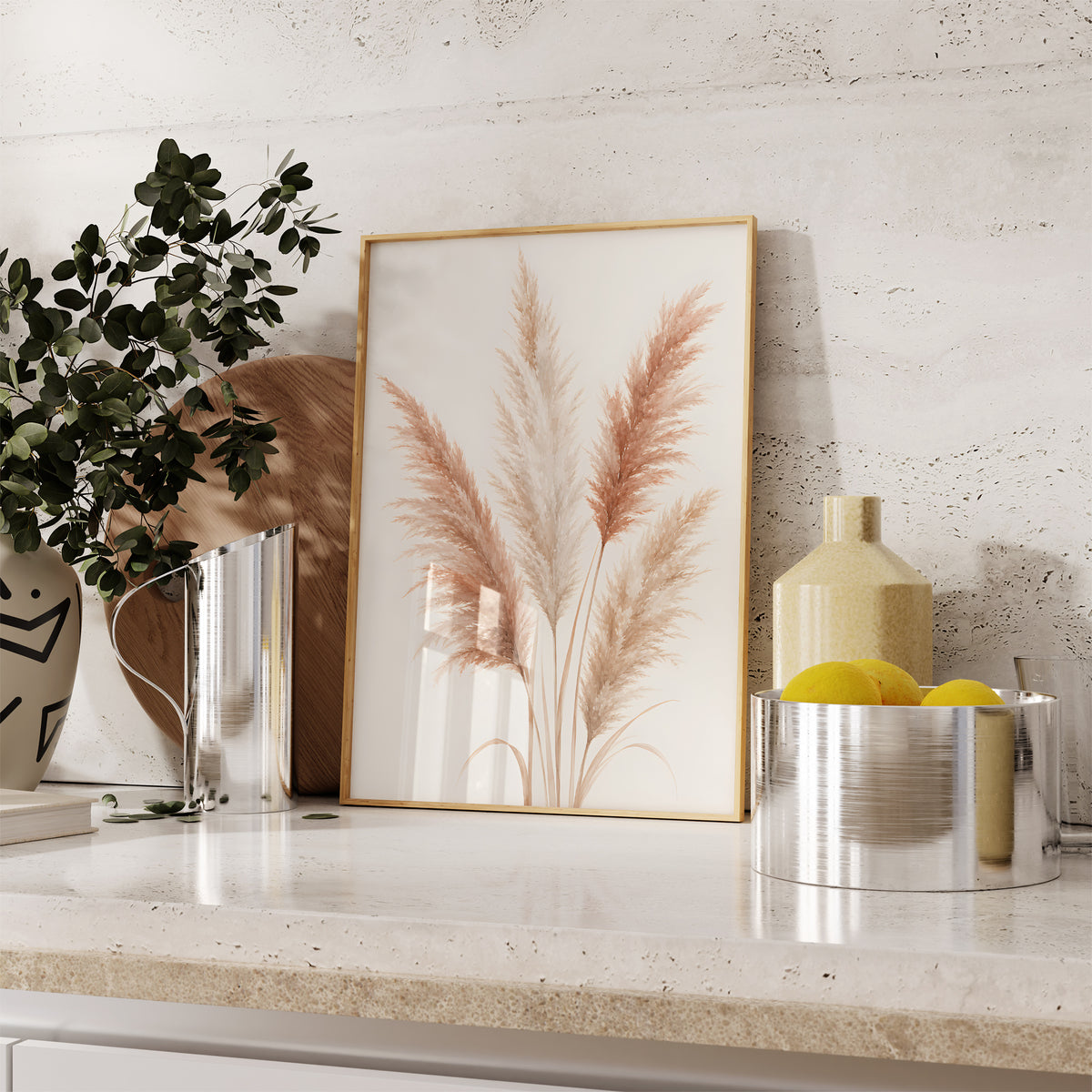 Gerahmtes Poster mit einem illustrierten Pampasbouquet in Rosé und Creme, auf einer Küchenarbeitsplatte neben Pflanzen und Zitronen.
