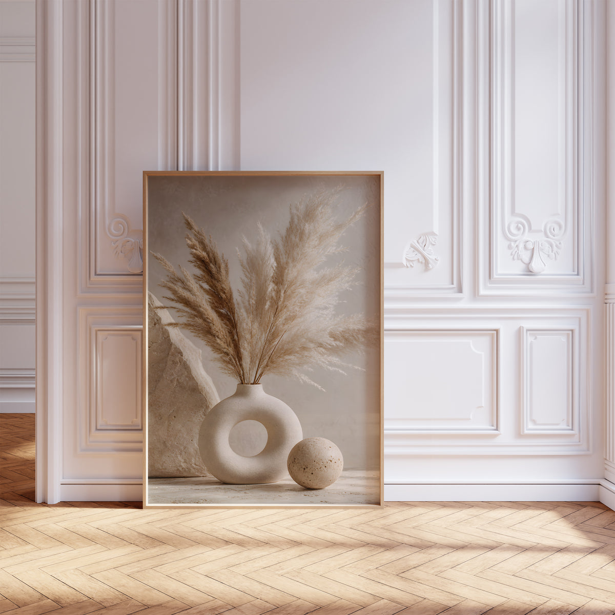 Gerahmtes Poster mit einem cremebraunen Pampasbouquet in einer weißen Ringvase neben einer Steinkugel, vor einer weißen Wand mit Zierleisten.