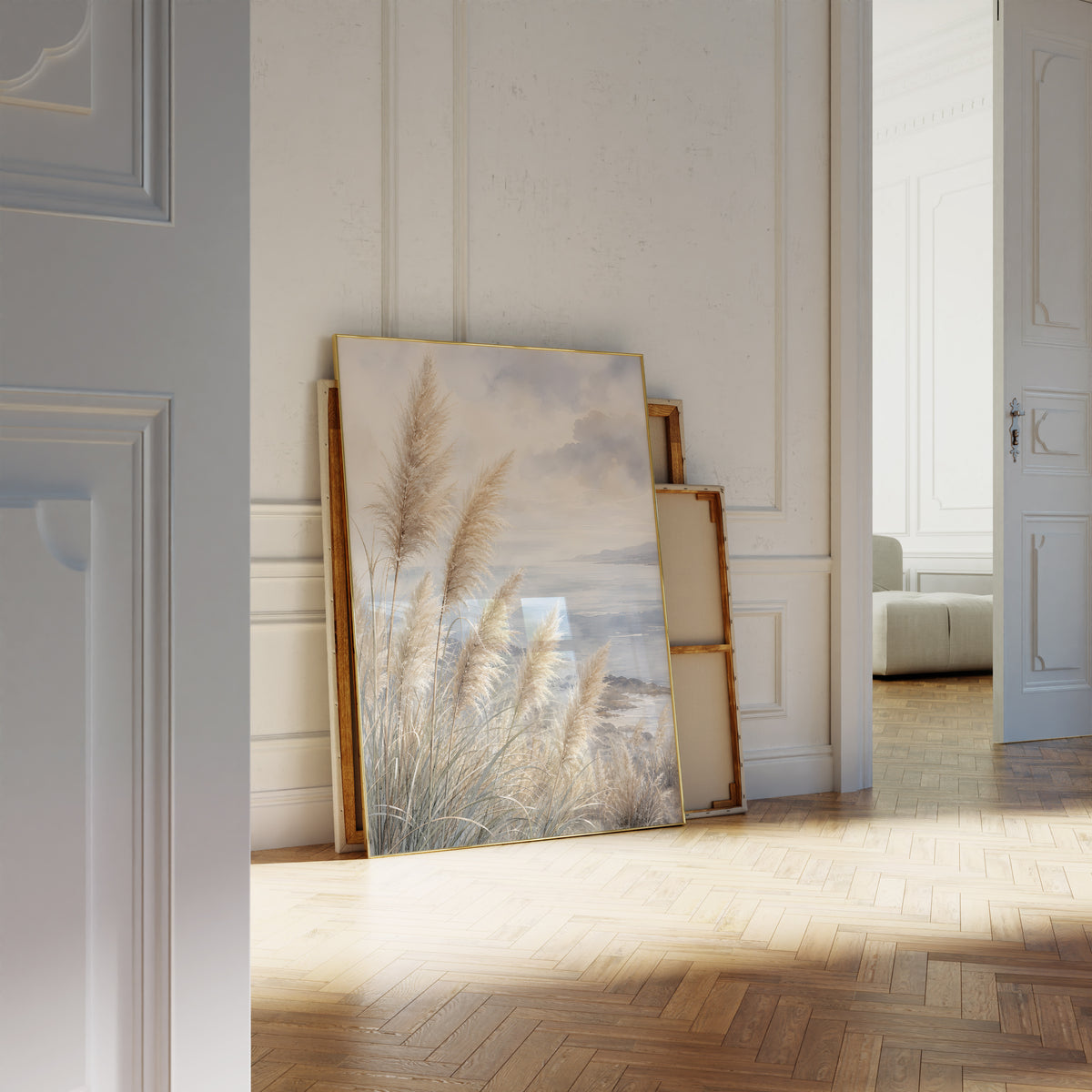Motiv mit Pampasgräsern an einer blauen Küste unter Wolken in Aquarelloptik, als an die Wand gelehntes Poster neben leeren Rahmen.
