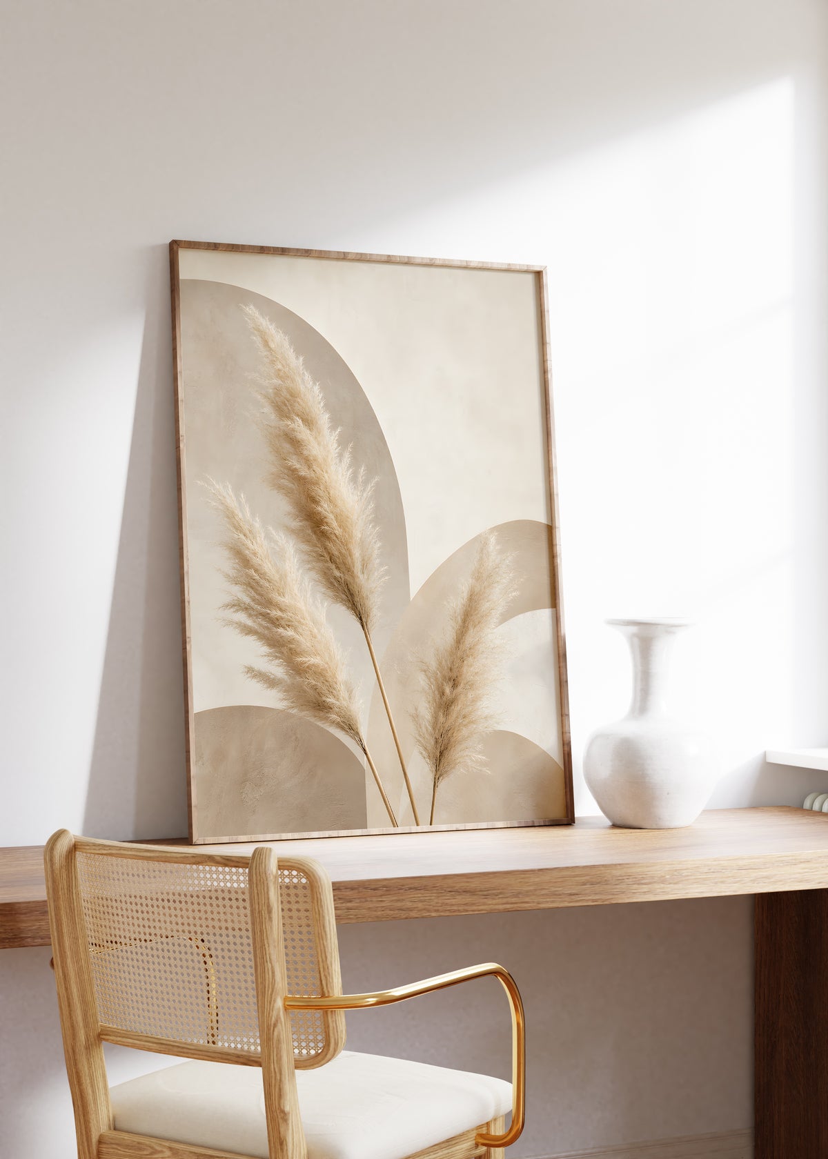 Gerahmtes Poster mit hellen Pampaswedeln vor überlappenden beigefarbenen Bögen, auf einem Holztisch neben einer weißen Vase.