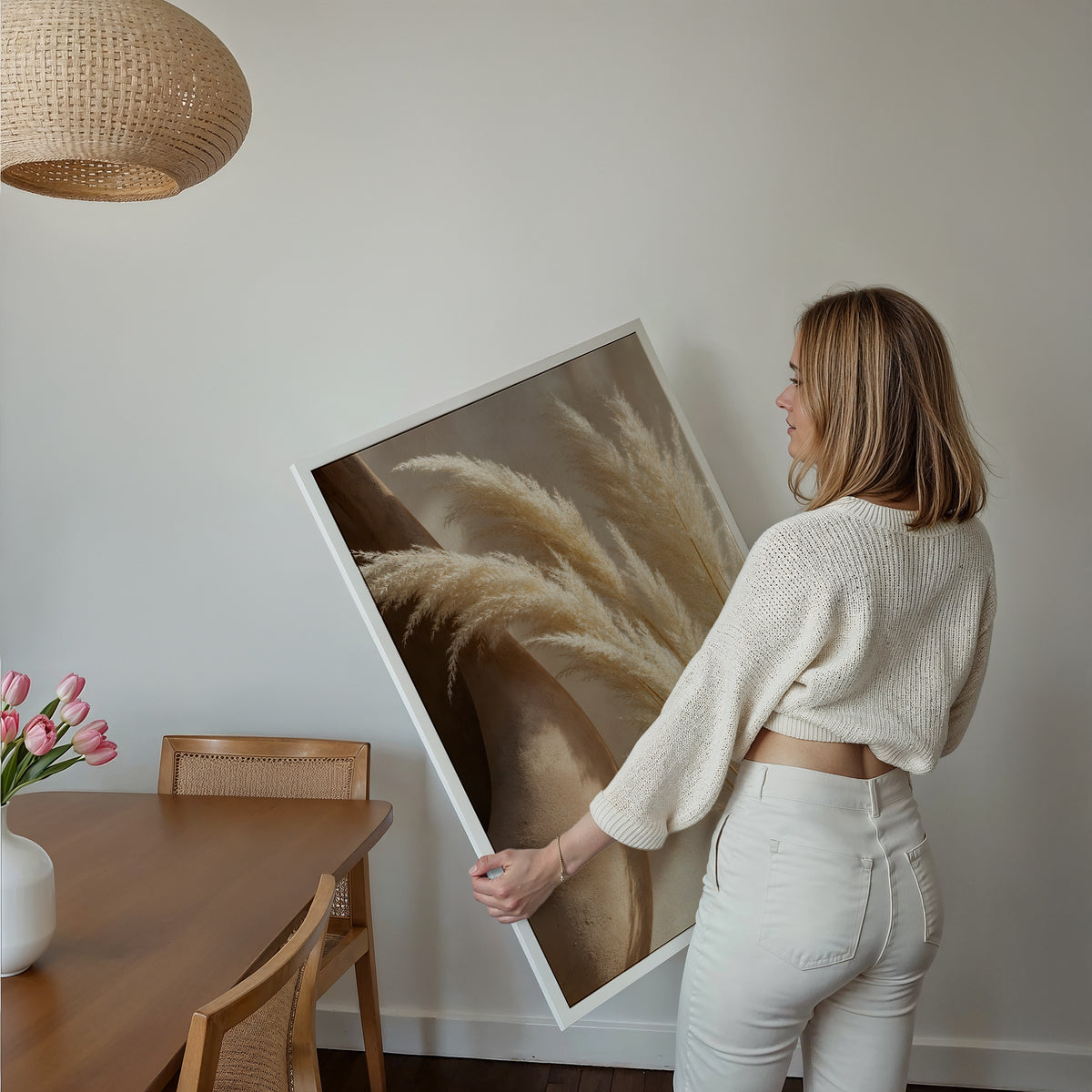 Motiv mit hellen Pampaswedeln neben einer großen braunen Tonvase, über einem Bett im hellen Schlafzimmer.