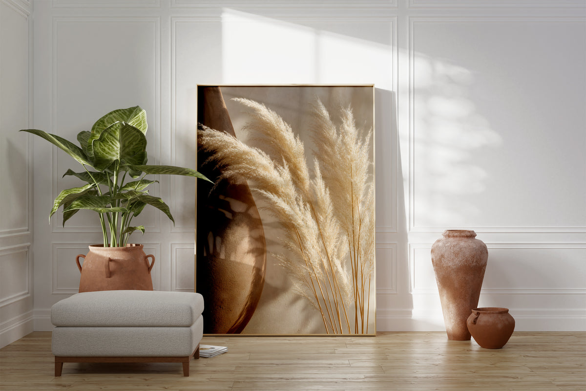 Motiv mit hellen Pampaswedeln neben einer großen braunen Tonvase, als gerahmtes Poster neben Sessel und Zimmerpflanze.