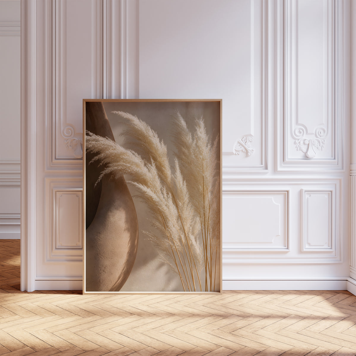 Gerahmtes Poster mit hellen Pampaswedeln neben einer großen braunen Tonvase, vor einer weißen Wand mit Zierleisten.