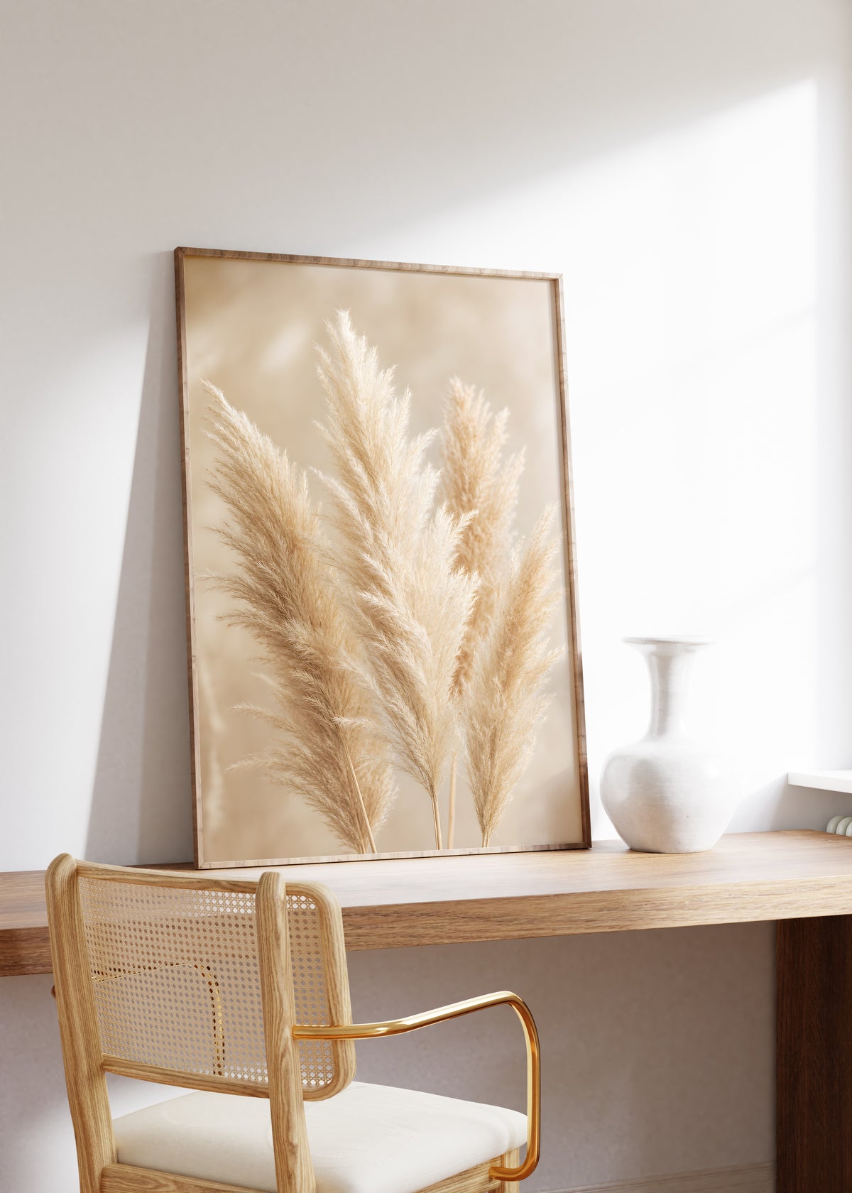 Gerahmtes Poster mit mehreren flauschigen Pampaswedeln in Creme und Beige vor weich verschwommenem Hintergrund, auf einem Holztisch neben einer weißen Vase.