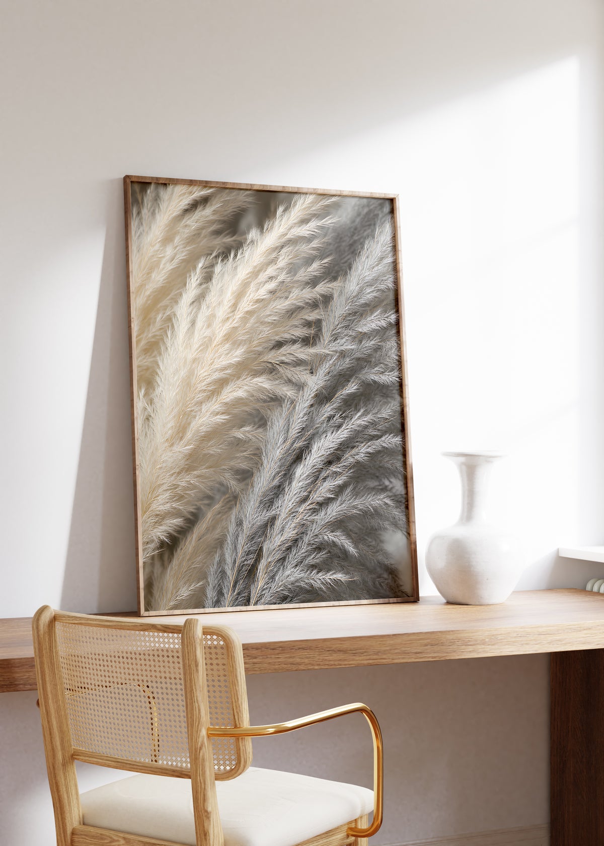 Gerahmtes Poster mit einer dichten Nahaufnahme von Pampasfasern in Beige und Silbergrau, auf einem Holztisch neben einer weißen Vase.