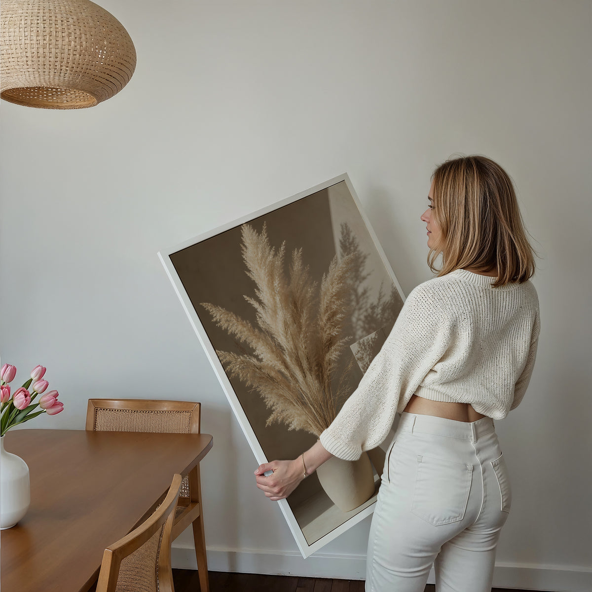 Motiv mit einer hellen Vase mit Pampasgras neben geometrischen Steinformen und Schatten, über einem Bett im hellen Schlafzimmer.