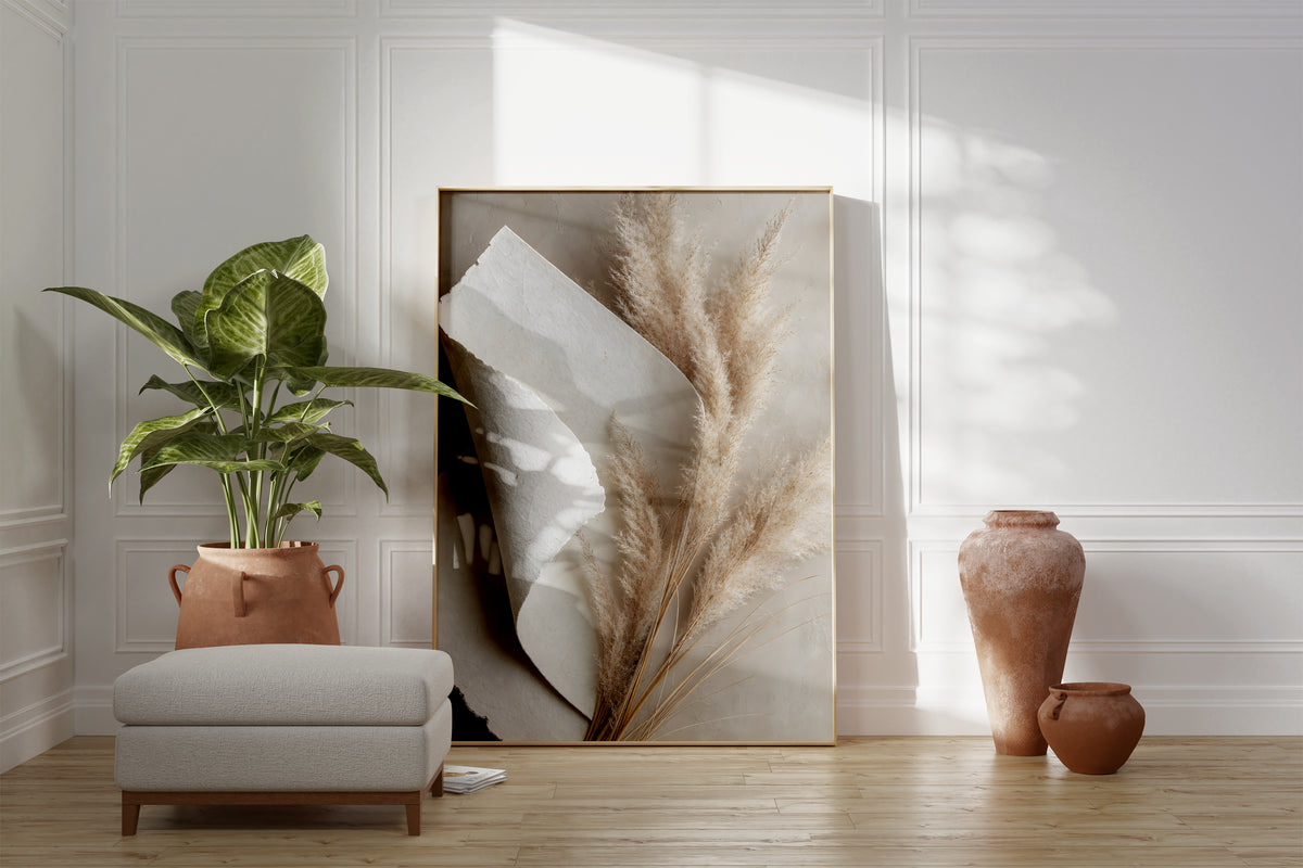Motiv mit beigen Pampaswedeln neben gefaltetem weißem Naturpapier, als gerahmtes Poster neben Sessel und Zimmerpflanze.