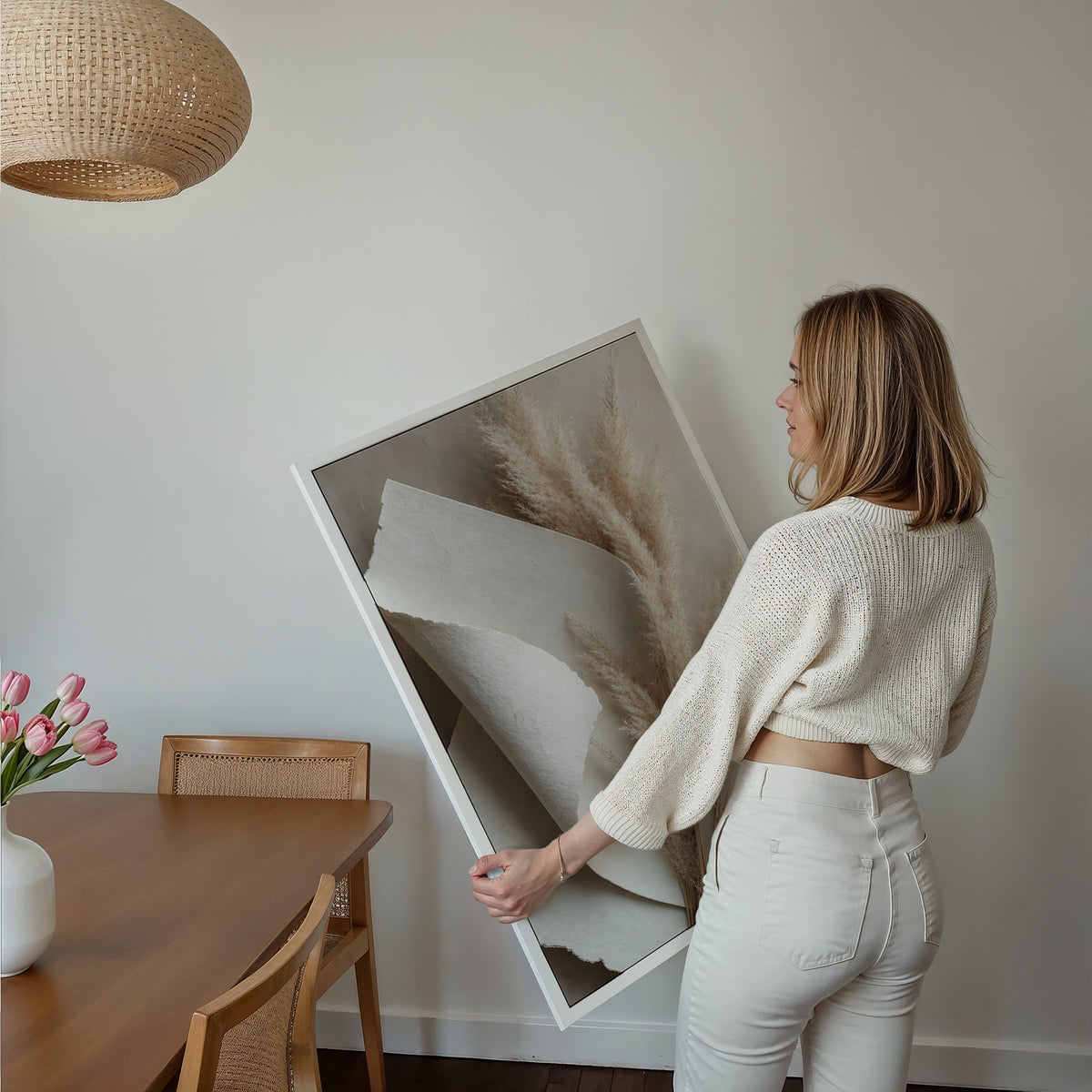 Motiv mit beigen Pampaswedeln neben gefaltetem weißem Naturpapier, über einem Bett im hellen Schlafzimmer.