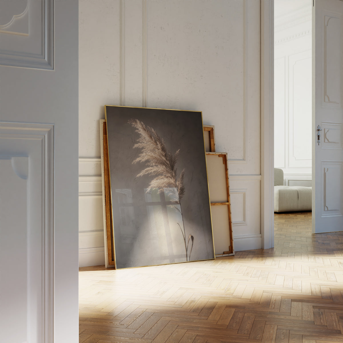 Motiv mit einem braunbeigen Pampaswedel vor dunklem Hintergrund mit einem hellen Lichtfleck, als an die Wand gelehntes Poster neben leeren Rahmen.