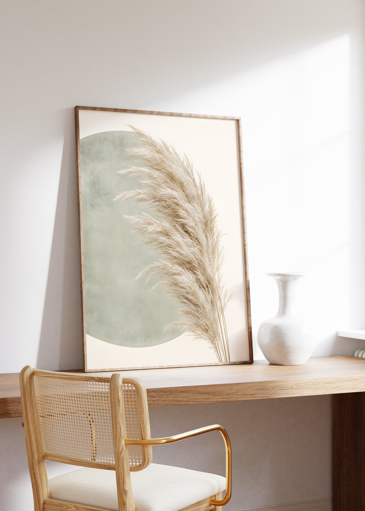 Gerahmtes Poster mit einem hellen gebogenen Pampaswedel vor einer salbeigrünen organischen Form, auf einem Holztisch neben einer weißen Vase.
