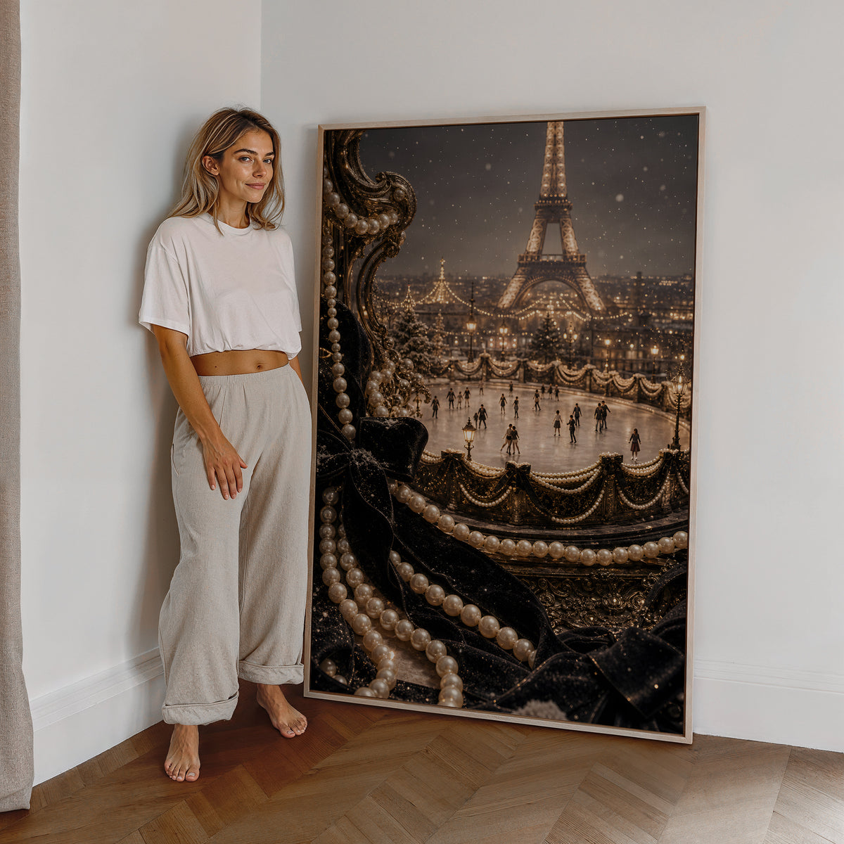 Motiv mit einer beleuchteten Pariser Eisbahn vor dem Eiffelturm, umrahmt von Perlen und schwarzem Samt, als großes gerahmtes Wandbild neben einer Frau.