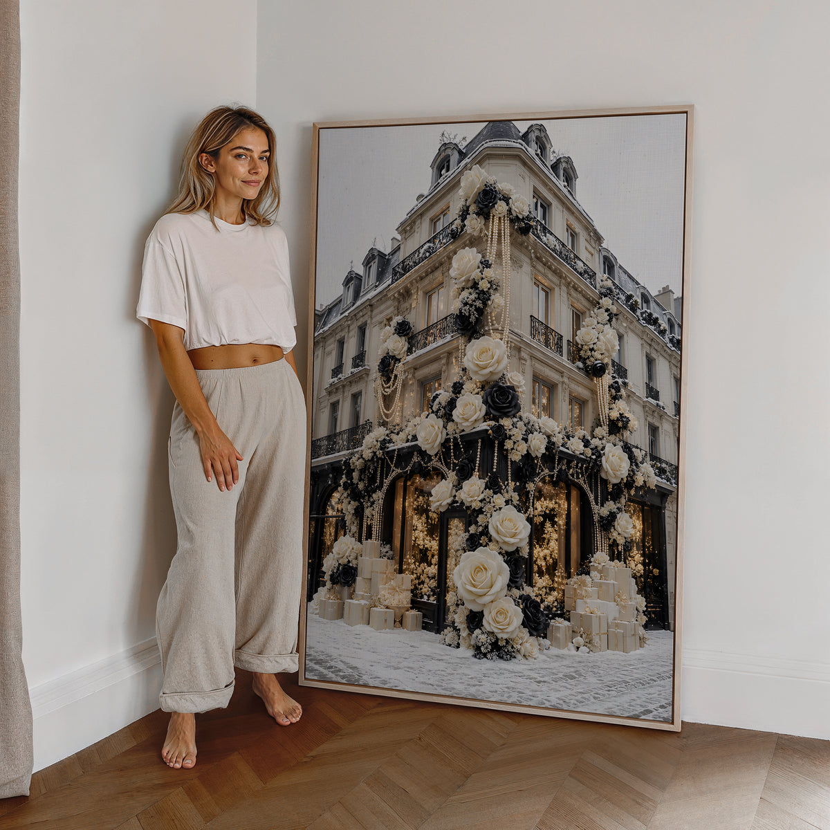 Motiv mit einer Pariser Hausfassade mit weißen und schwarzen Rosen im Schnee, als großes gerahmtes Wandbild neben einer Frau.