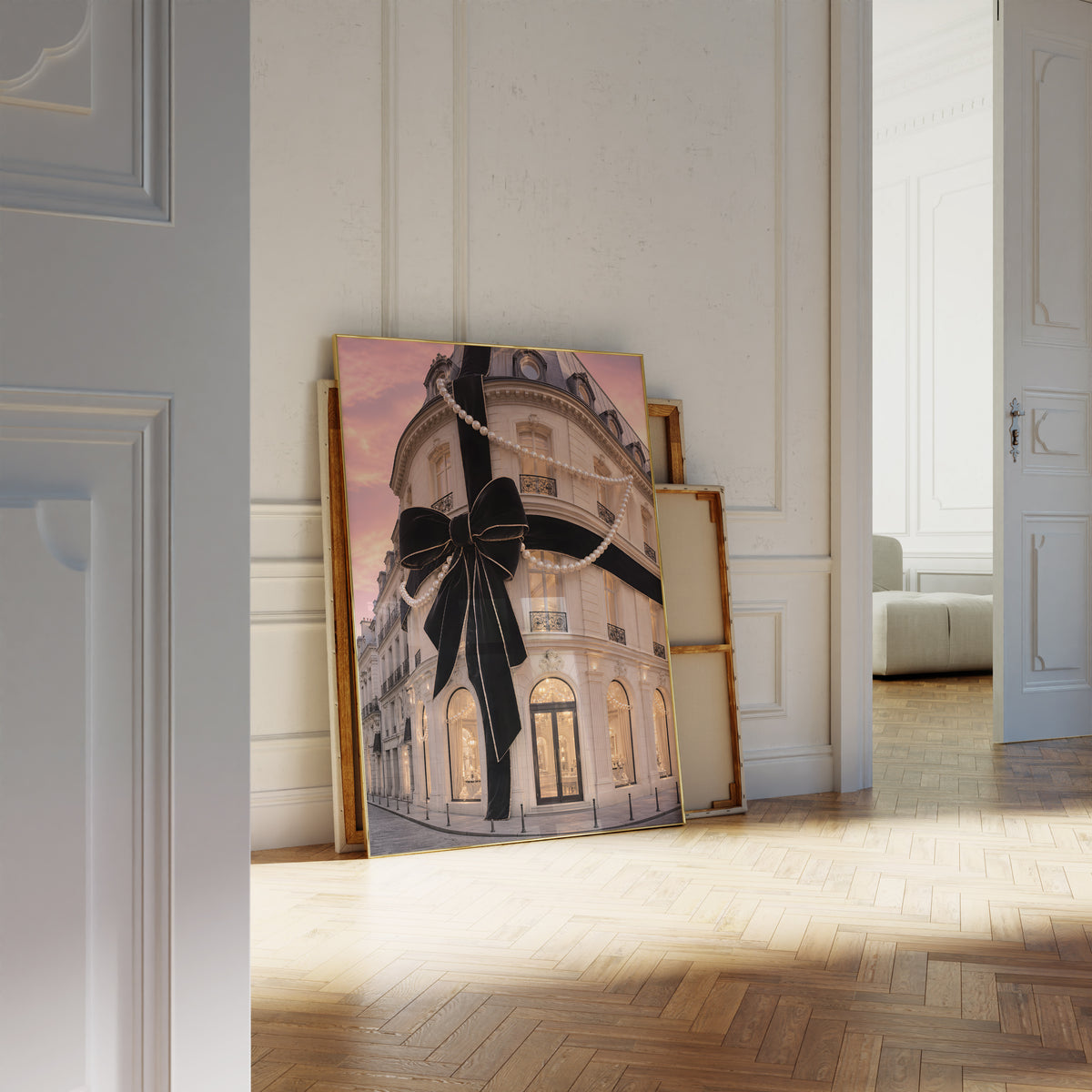 Motiv mit Pariser Hausfassade mit großer schwarzer Schleife und Perlenketten unter rosafarbenem Himmel, als an die Wand gelehntes Poster neben leeren Rahmen.