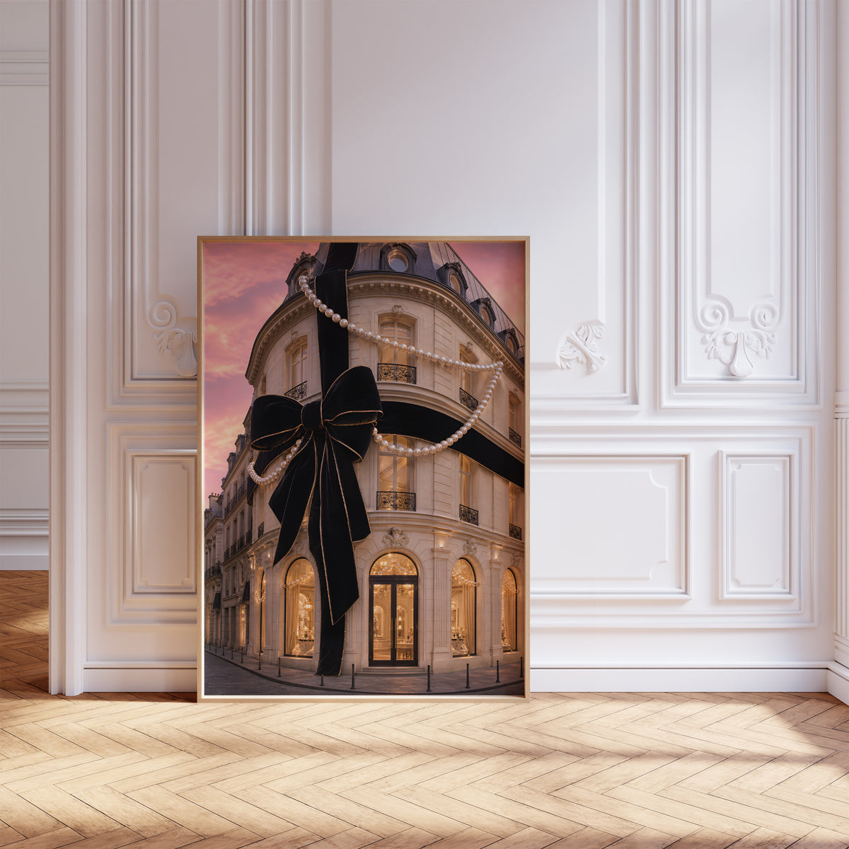 Gerahmtes Poster mit Pariser Hausfassade mit großer schwarzer Schleife und Perlenketten unter rosafarbenem Himmel, als einzelne Wanddekoration in einer Wohnraumansicht.