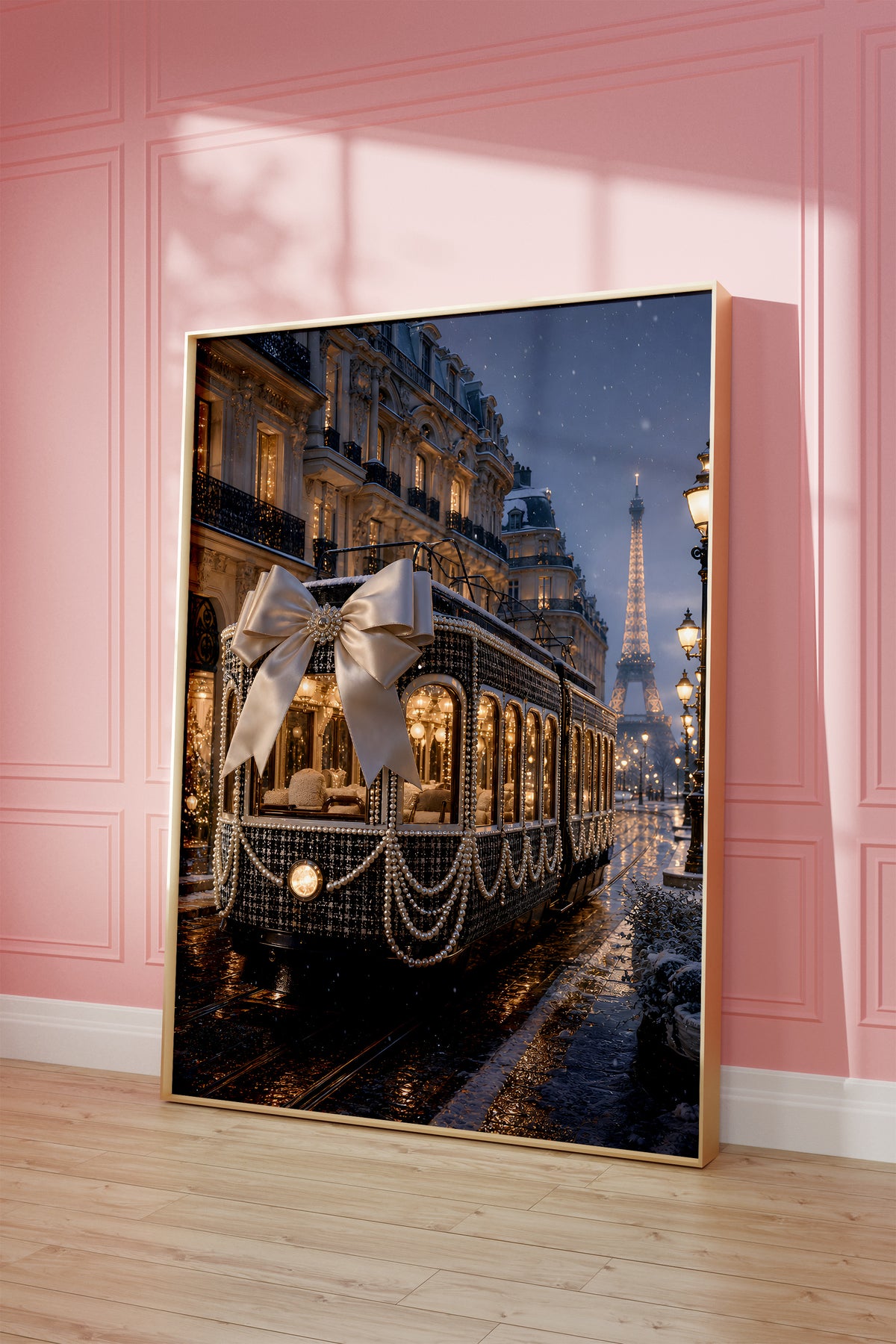 Motiv mit dunkler Pariser Straßenbahn mit großer Satinschleife und Perlenketten im Abendlicht, als gerahmtes Poster vor einer rosafarbenen Wand.
