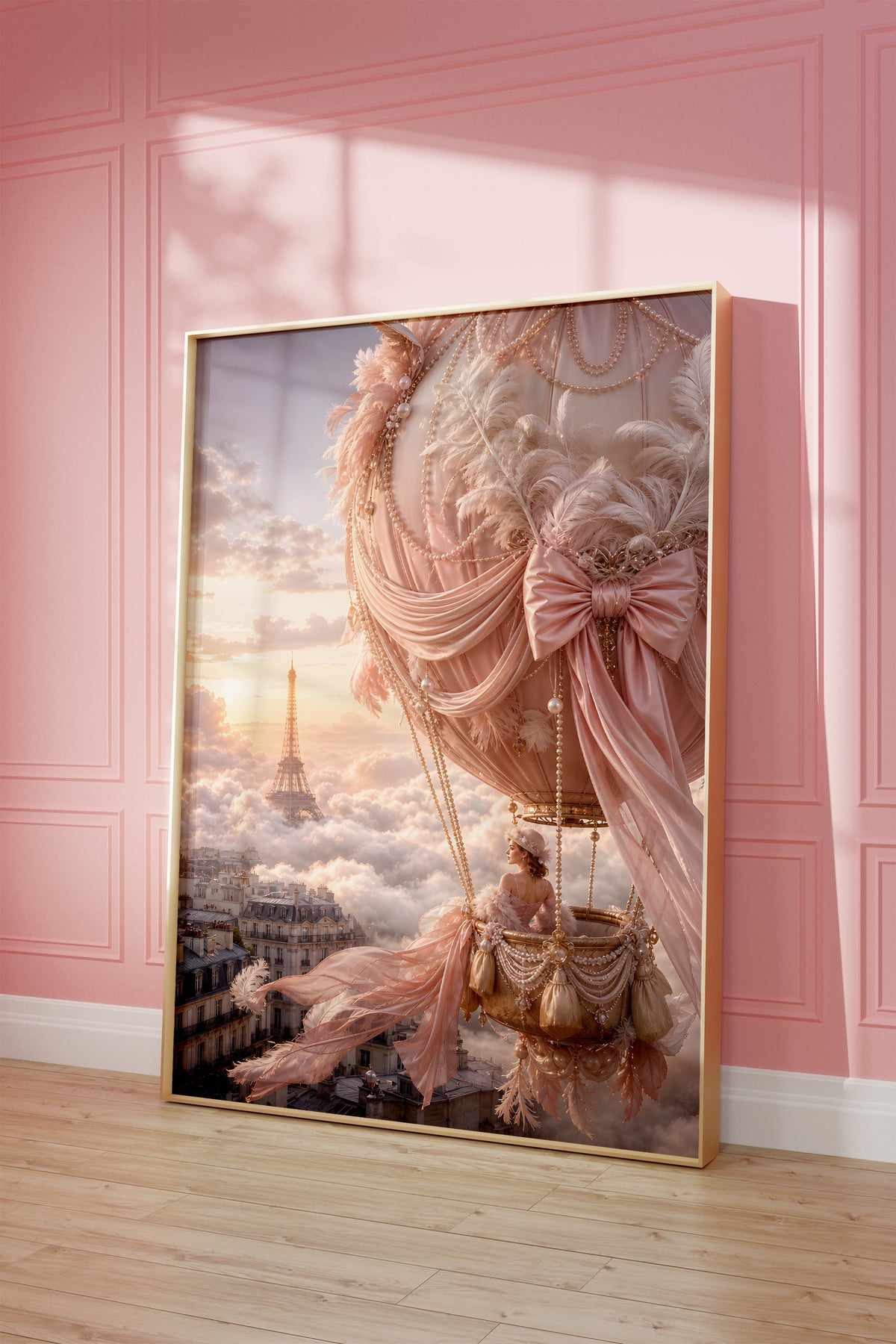 Motiv mit rosafarbenem Heißluftballon mit Perlen und Schleifen über Paris bei Sonnenuntergang, als gerahmtes Poster vor einer rosafarbenen Wand.
