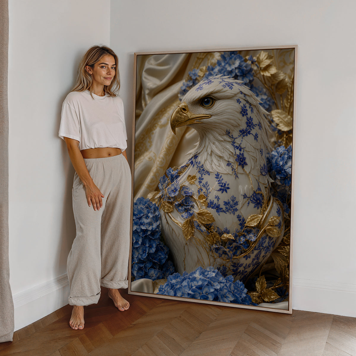 Motiv mit einem weiß-blauen Adler mit goldenem Schnabel und blauen Hortensien, als großes gerahmtes Wandbild neben einer Frau.