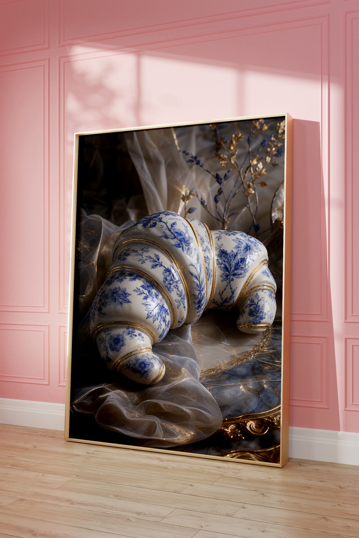 Motiv mit einem weiß-blauen Croissant in Porzellanoptik mit goldenen Verzierungen, als gerahmtes Poster vor einer rosafarbenen Wand.
