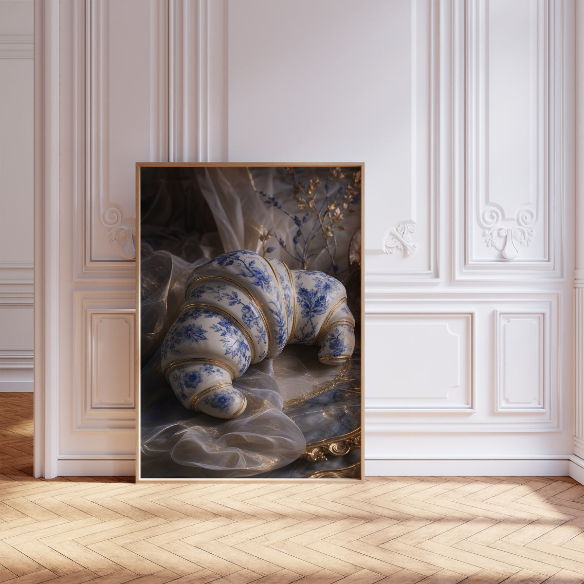 Gerahmtes Poster mit einem weiß-blauen Croissant in Porzellanoptik mit goldenen Verzierungen, vor einer weißen Wand mit Zierleisten.