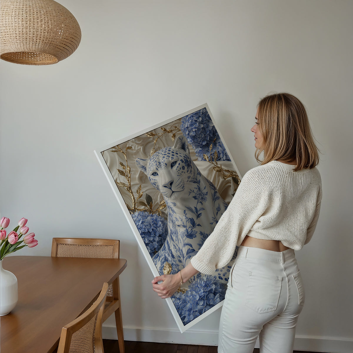 Motiv mit weißem Panther mit blauem Porzellanmuster zwischen Hortensien und goldenen Zweigen, als gerahmtes Poster in den Händen einer Frau.