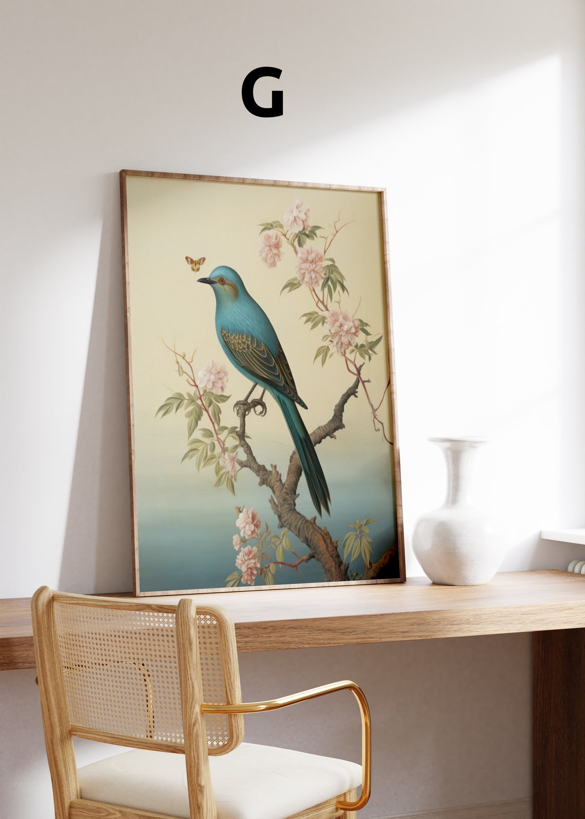 Postermotiv G: Blauer Vogel auf einem blühenden Ast vor warmem cremefarbenem Hintergrund. Im Holzrahmen auf einem Schreibtisch.