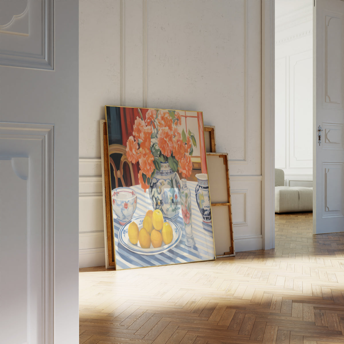 Gerahmtes Poster neben einer großen weißen Vase an einer Wand mit Zierleisten. Motiv: Orangefarbene Blumen in einer blau-weißen Vase neben Zitronen.