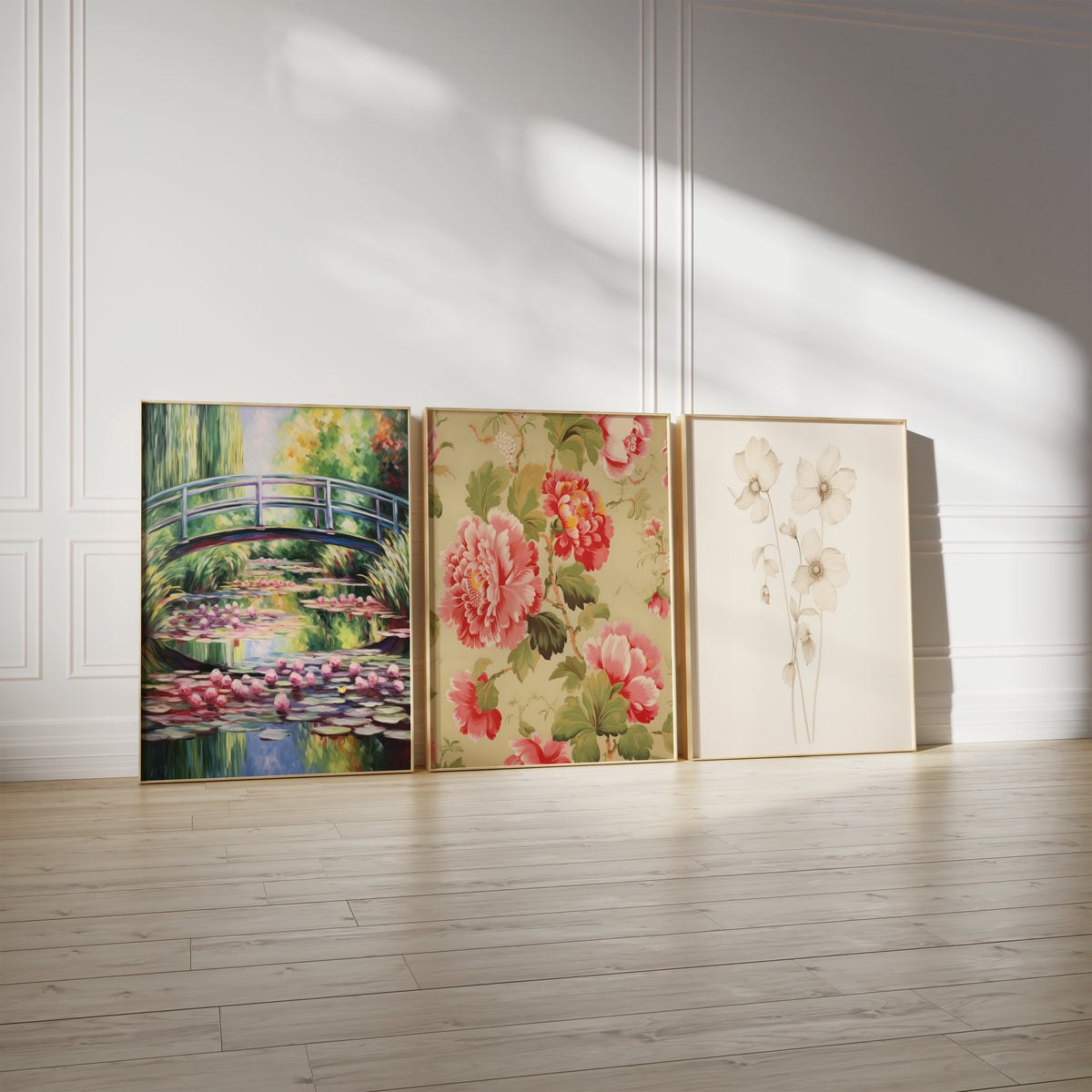 Drei gerahmte Poster an einer hellen Wand mit Zierleisten. Motive: Geschwungene Brücke über einem Teich mit rosa Seerosen und grünen Weidenzweigen; Florales Muster mit roten und rosa Pfingstrosen und grünen Blättern; Zarte weiße Blüten an langen Stielen vor cremefarbenem Hintergrund.