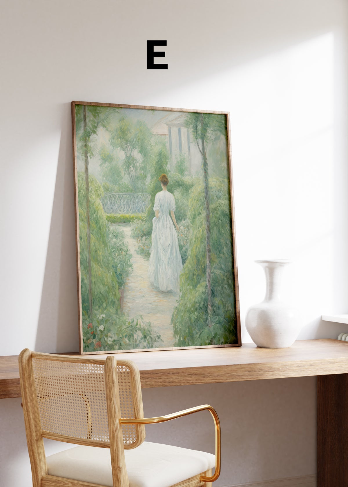 Postermotiv E: Frau im weißen Kleid auf einem von Pflanzen umgebenen Gartenweg. Im Holzrahmen auf einem Schreibtisch.
