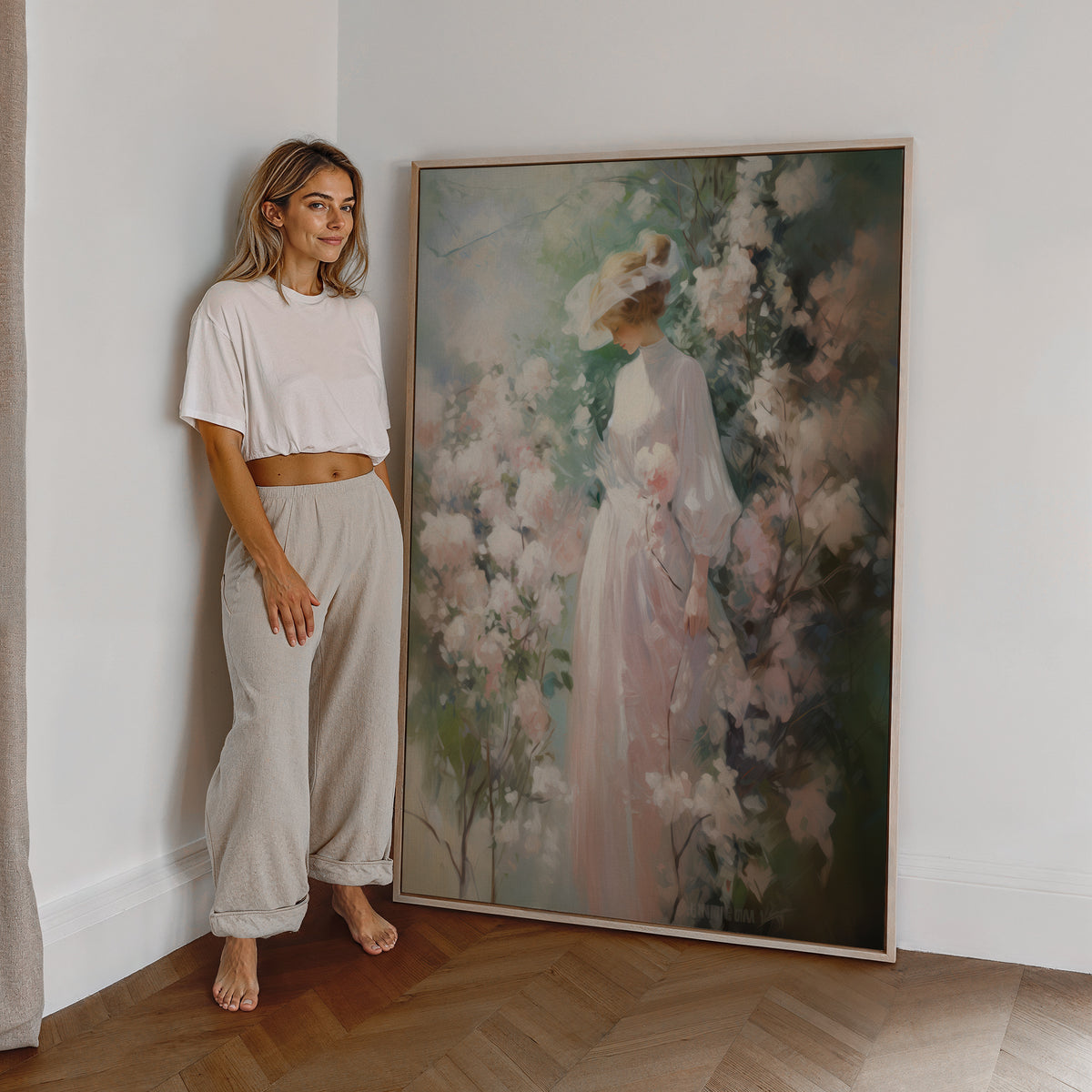 Eine Frau steht neben einem großen gerahmten Poster. Motiv: Eine Frau im rosa Kleid und Sonnenhut zwischen üppigen Blüten.