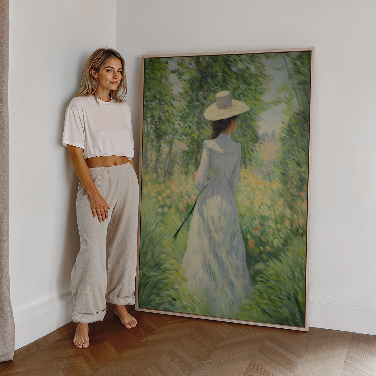 Eine Frau steht neben einem großen gerahmten Poster. Motiv: Eine Frau im hellen Kleid und Sonnenhut auf einer sommerlichen Blumenwiese.