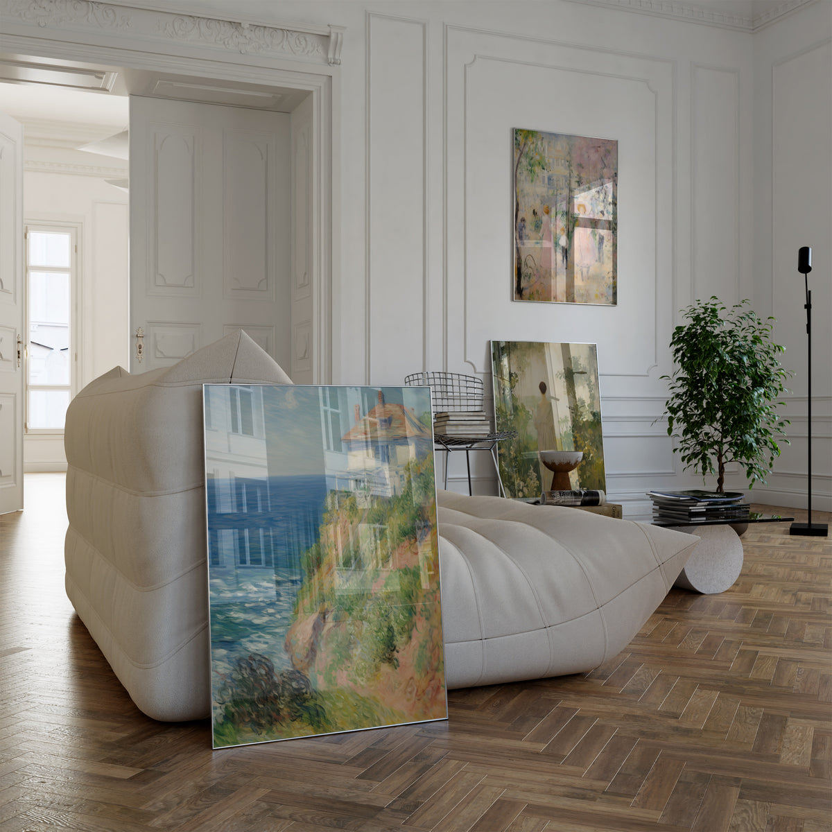 Poster in einem hellen Wohnzimmer mit weißem Sofa. Motive: Helles Haus an einer begrünten Steilküste über dem blauen Meer; Frauen und Kinder beim Spaziergang unter rosa blühenden Bäumen; Eine Frau im hellen Kleid in einem verträumten Garten mit weißen Blüten.