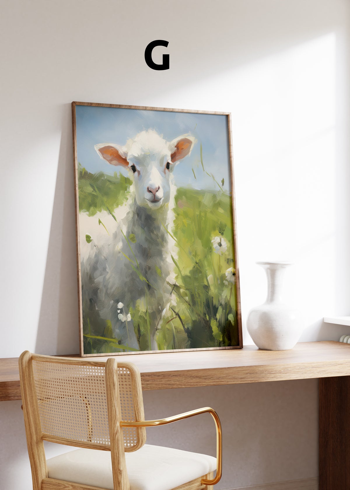 Postermotiv G: Weißes Lamm auf einer grünen Wiese mit kleinen weißen Blumen. Im Holzrahmen auf einem Schreibtisch.
