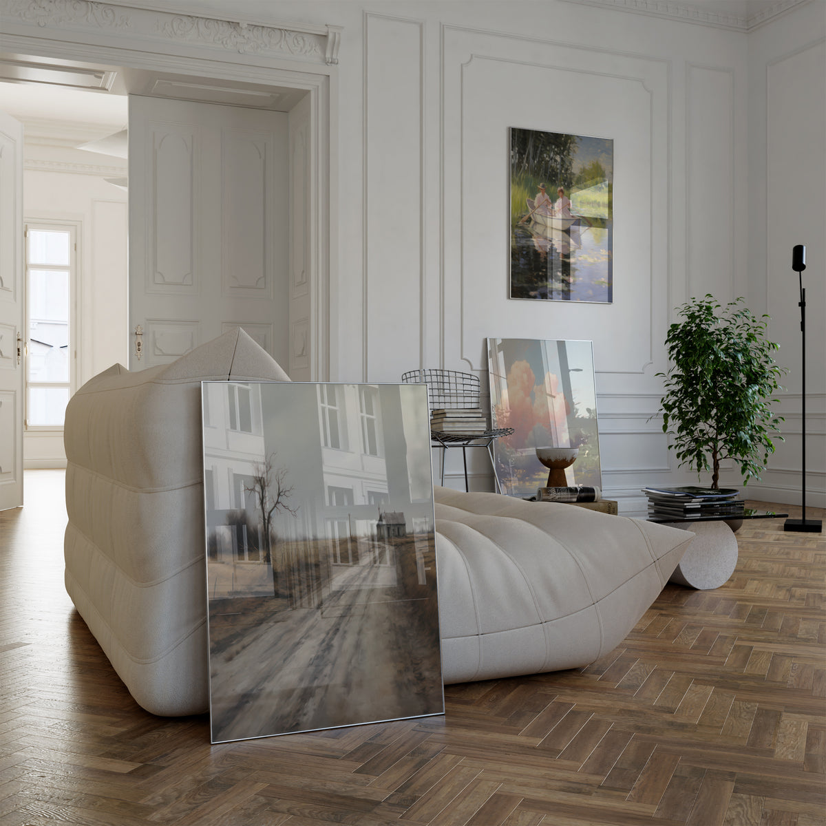 Poster in einem hellen Wohnzimmer mit weißem Sofa. Motive: Ländlicher Weg zu einem einsamen Haus unter grauem Himmel; Zwei Frauen in einem Ruderboot auf einem ruhigen Gewässer; Rosa Wolken über einer weiten Flusslandschaft.