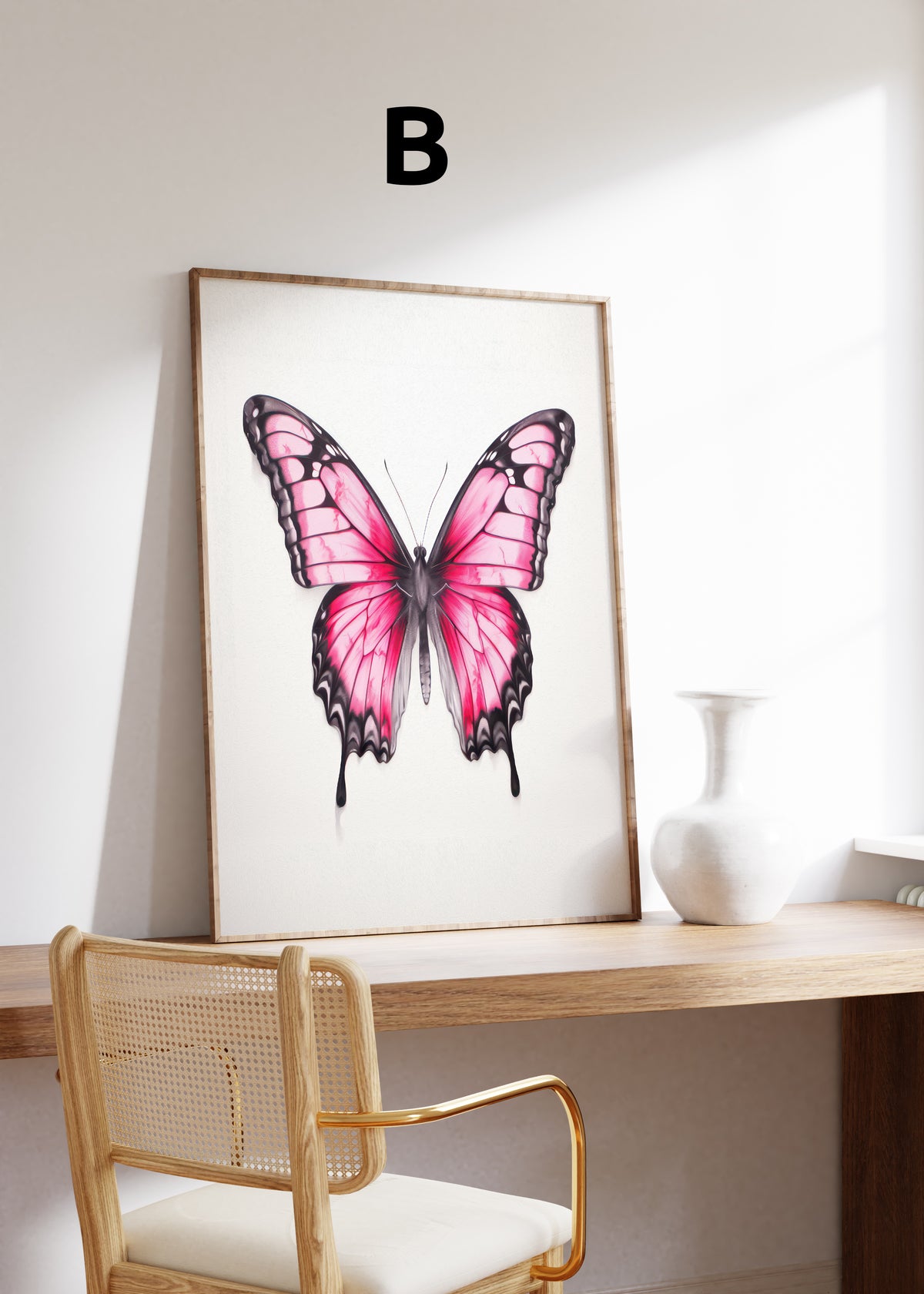 Postermotiv B: Rosa Schmetterling mit schwarz umrandeten Flügeln auf hellem Hintergrund. Im Holzrahmen auf einem Schreibtisch.