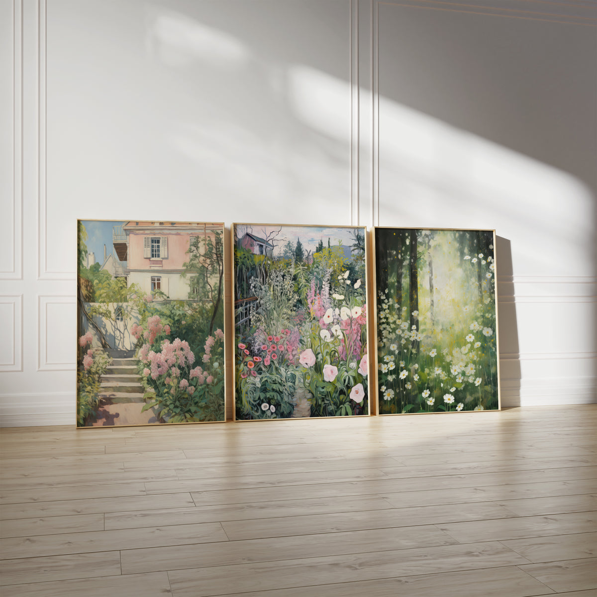 Drei gerahmte Poster an einer hellen Wand mit Zierleisten. Motive: Steintreppe mit rosa Blüten vor einem hellen Haus; Üppiger Garten mit bunten Blumen und einem schmalen Weg; Weiße Margeriten in einem sonnendurchfluteten Wald.
