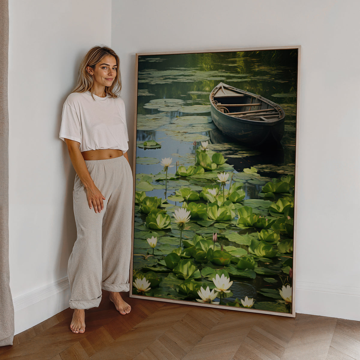 Eine Frau steht neben einem großen gerahmten Poster. Motiv: Dunkles Ruderboot auf einem grünen Teich mit weißen Seerosen.