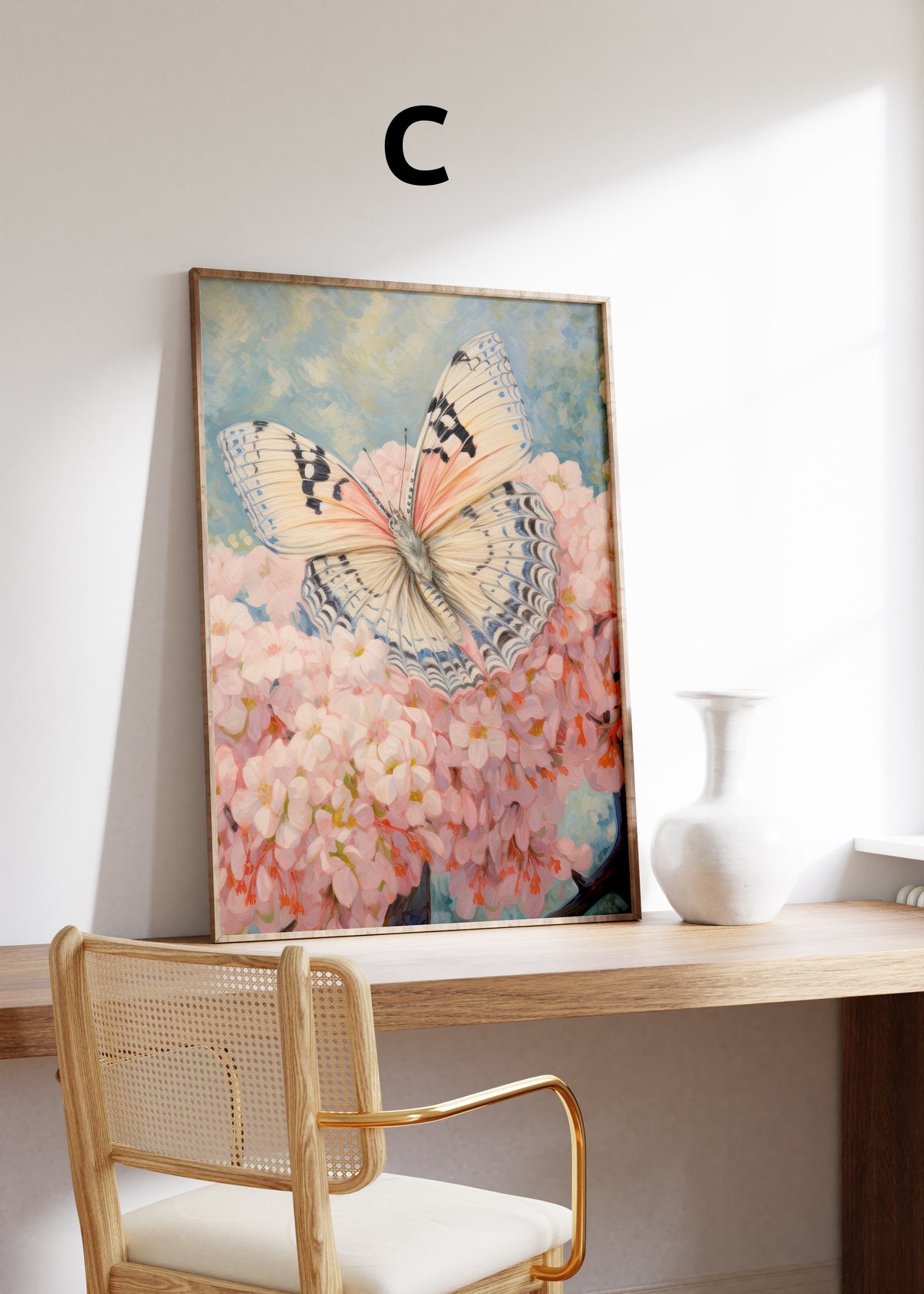 Postermotiv C: Heller Schmetterling mit feiner Flügelzeichnung auf rosa Blüten. Im Holzrahmen auf einem Schreibtisch.