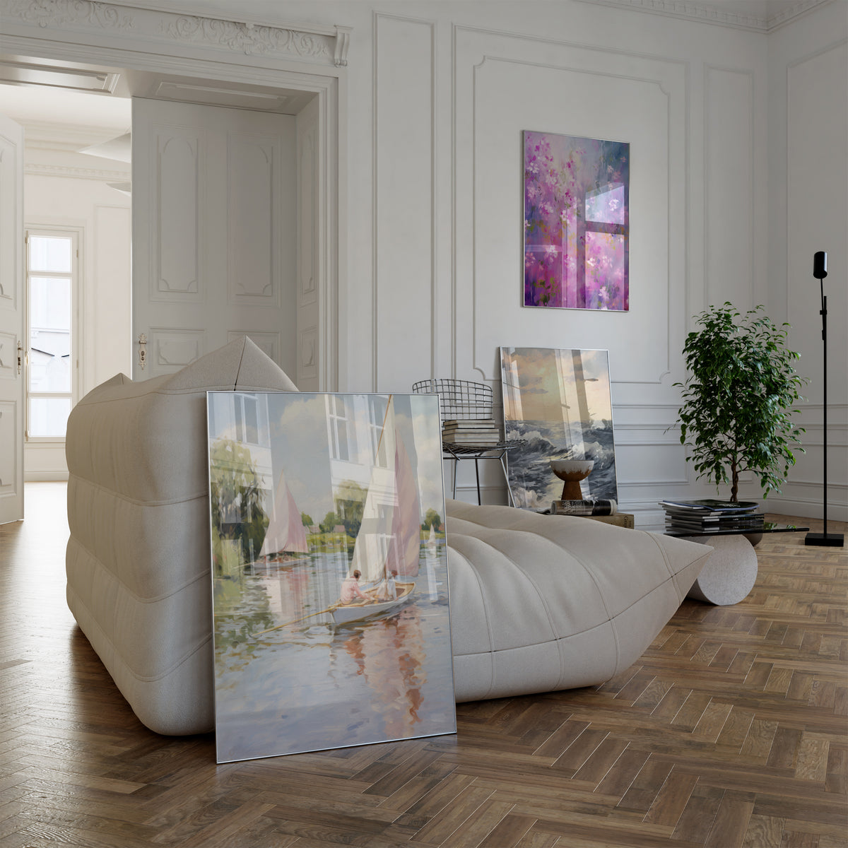 Poster in einem hellen Wohnzimmer mit weißem Sofa. Motive: Zwei Segelboote mit hellen Segeln auf einem sommerlichen Fluss; Leuchtende rosa und lila Blüten in einer lockeren Malerei; Blaue Meereswellen im warmen Abendlicht.