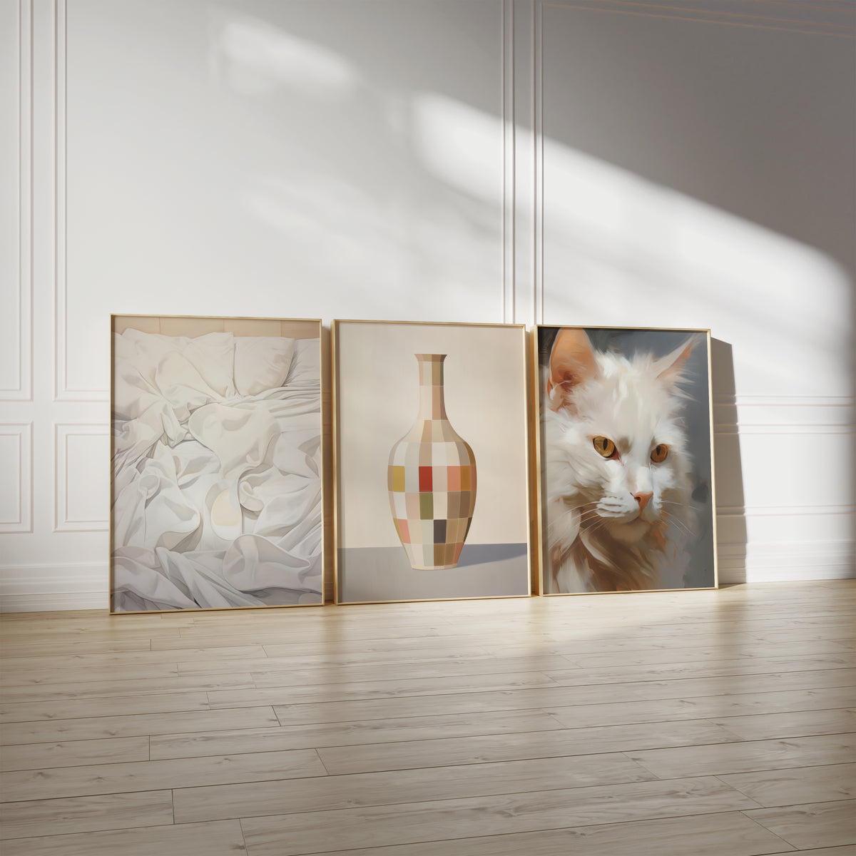 Drei gerahmte Poster an einer hellen Wand mit Zierleisten. Motive: Malerische Darstellung weißer Kissen und gefalteter Bettwäsche; Vase mit geometrischen Farbfeldern in Beige, Grün und Orange; Porträt einer weißen Katze mit goldbraunen Augen.