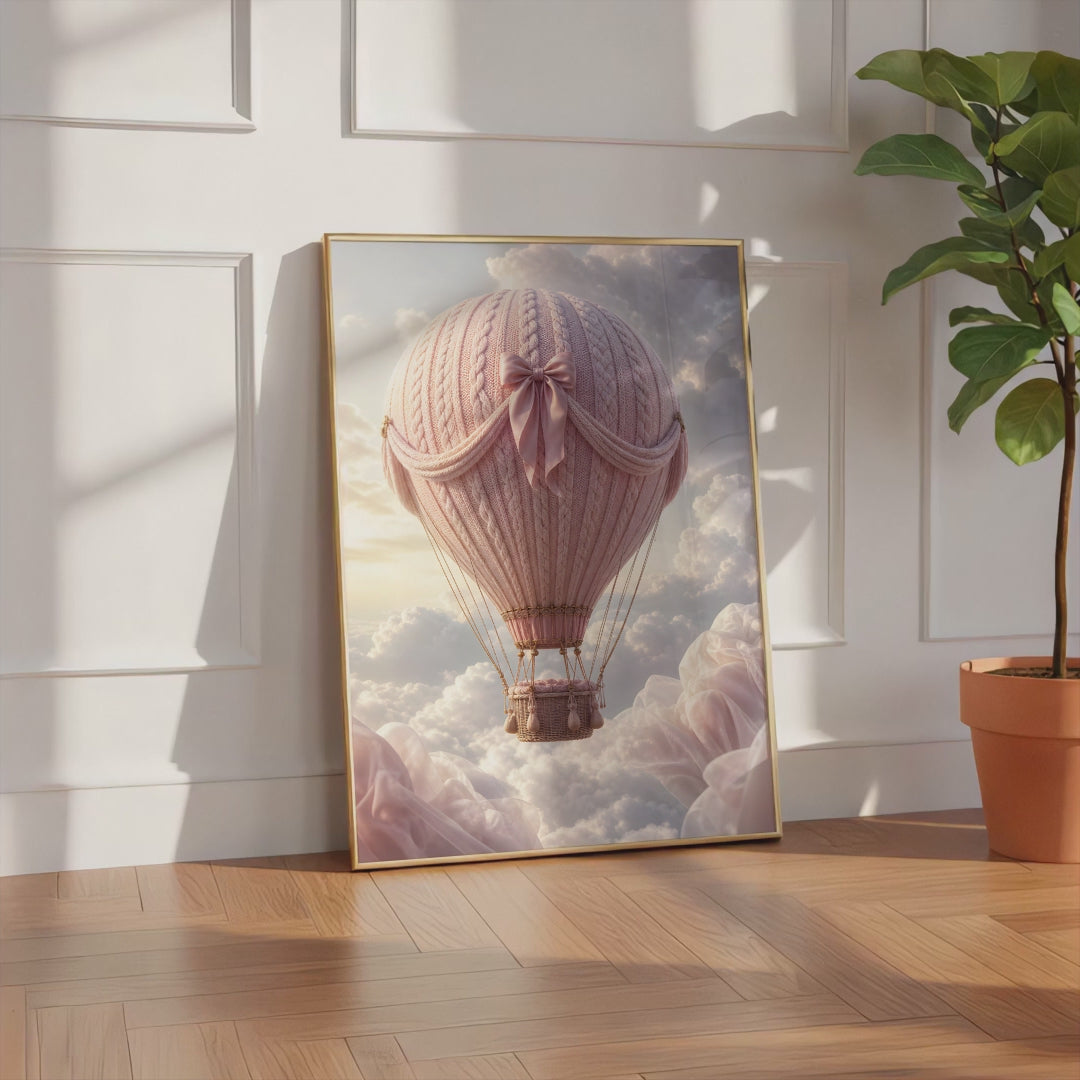 Videoansicht des gerahmten Posters mit einem rosafarbenen Heißluftballon in Strickoptik mit Satinschleife über Wolken.