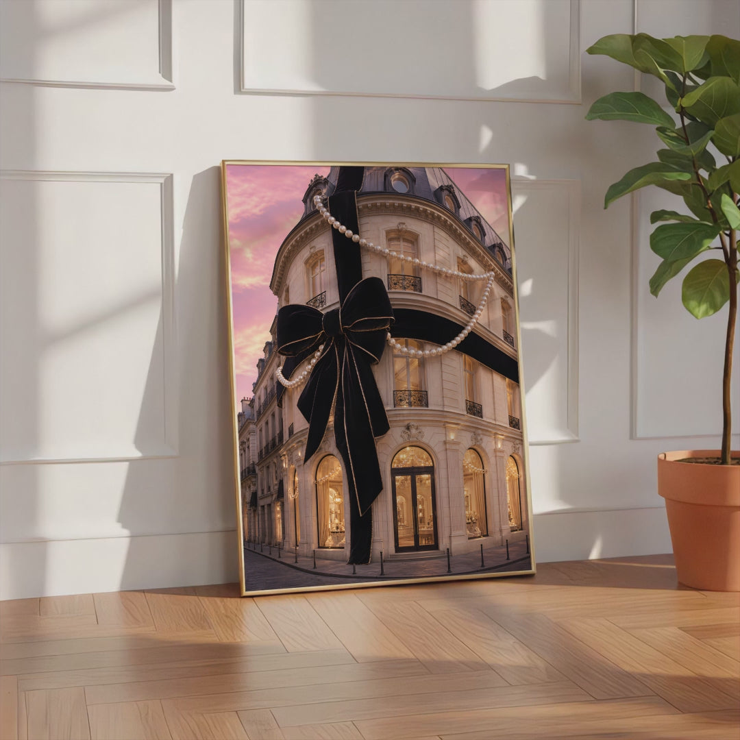 Videoansicht des gerahmten Posters mit Pariser Hausfassade mit großer schwarzer Schleife und Perlenketten unter rosafarbenem Himmel.