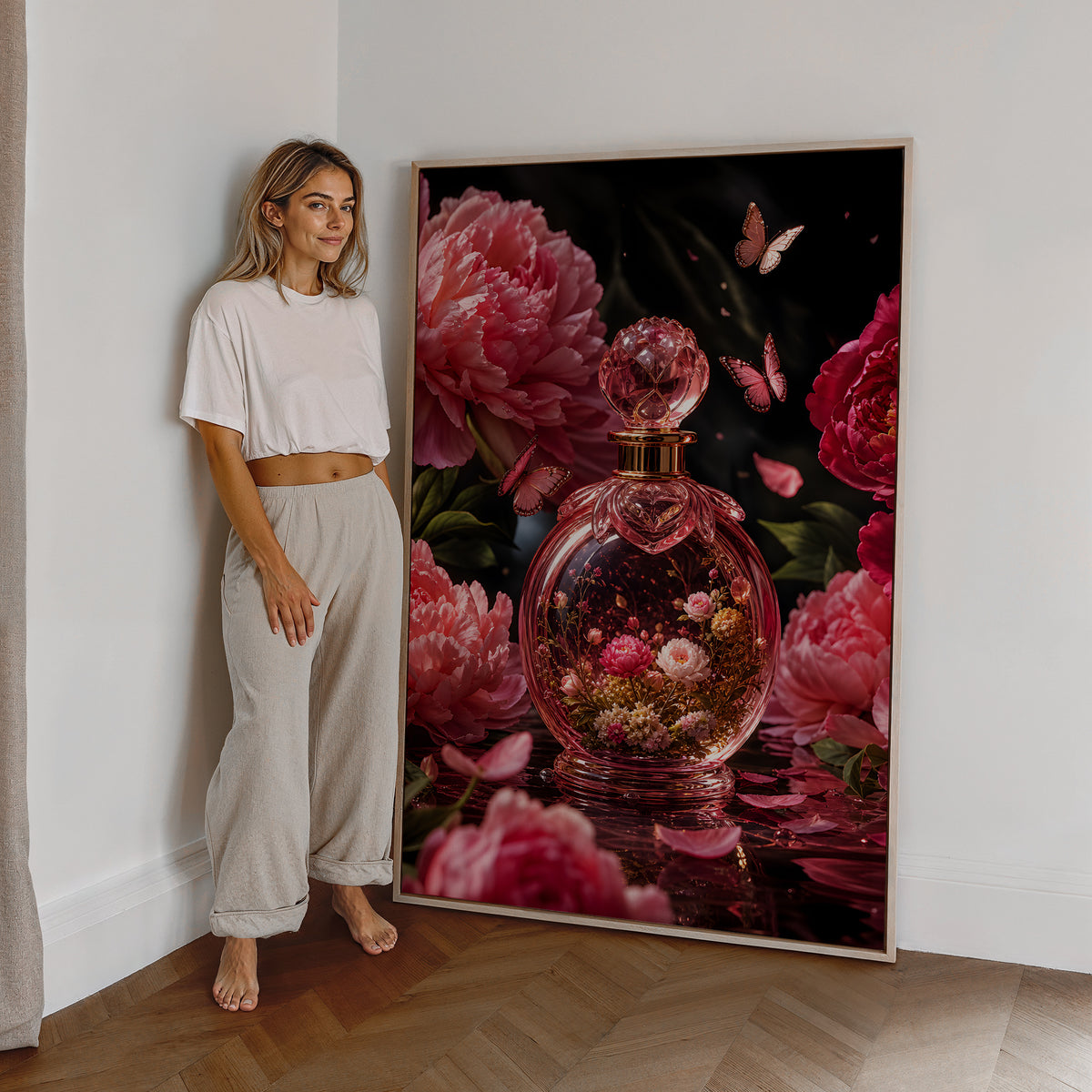 Motiv mit einem rosafarbenen Parfumflakon mit Blüten zwischen Pfingstrosen und Schmetterlingen, als großes gerahmtes Wandbild neben einer Frau.
