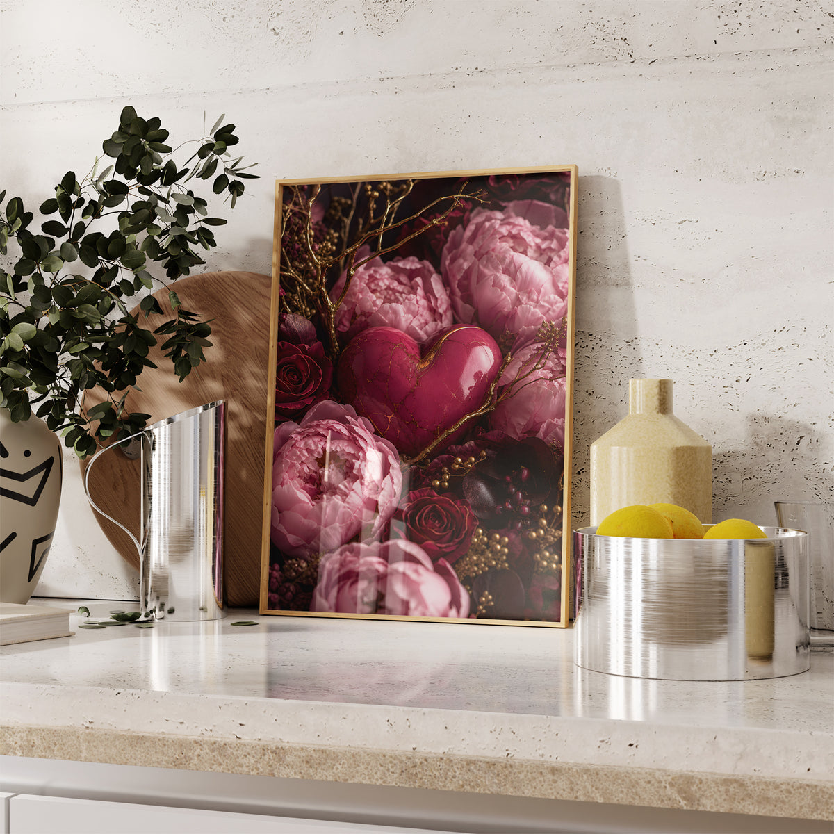 Gerahmtes Poster mit einem rosafarbenen Herz zwischen pinken Pfingstrosen, dunklen Rosen und goldenen Zweigen, auf einer Küchenarbeitsplatte neben Pflanzen und Zitronen.