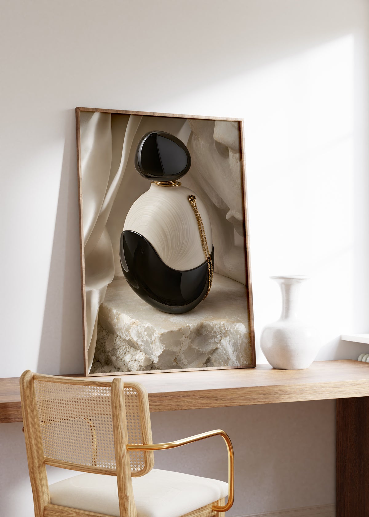 Gerahmtes Poster mit einem schwarz-weißen Parfumflakon mit einer goldenen Kette auf hellem Stein, auf einem Holztisch neben einer weißen Vase.