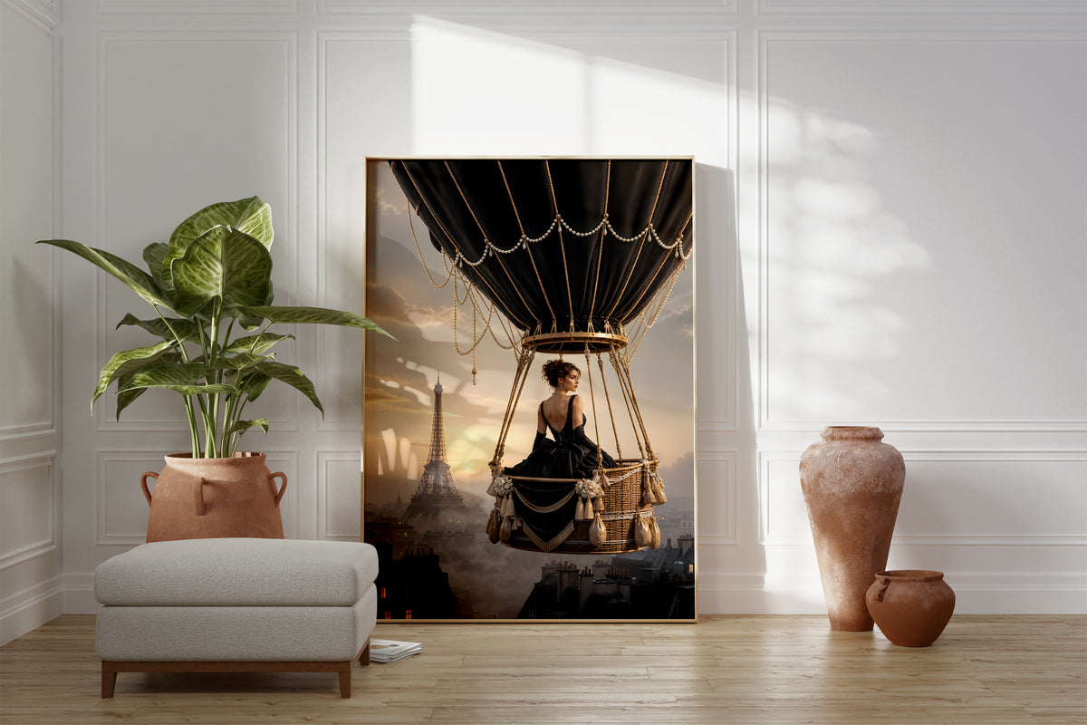 Motiv mit einer Frau im schwarzen Kleid im Korb eines schwarzen Heißluftballons über Paris, als gerahmtes Poster neben Sessel und Zimmerpflanze.