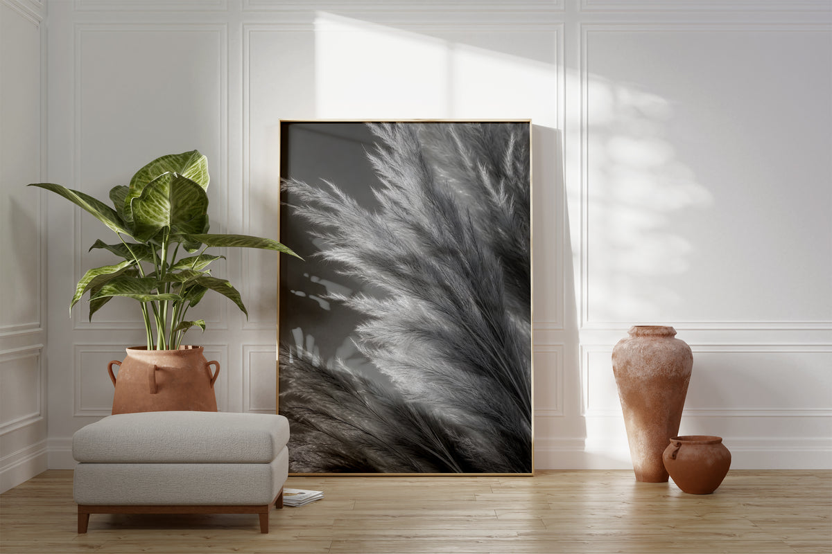 Motiv mit silbergrauen Pampasfasern in einer dichten monochromen Nahaufnahme, als gerahmtes Poster neben Sessel und Zimmerpflanze.