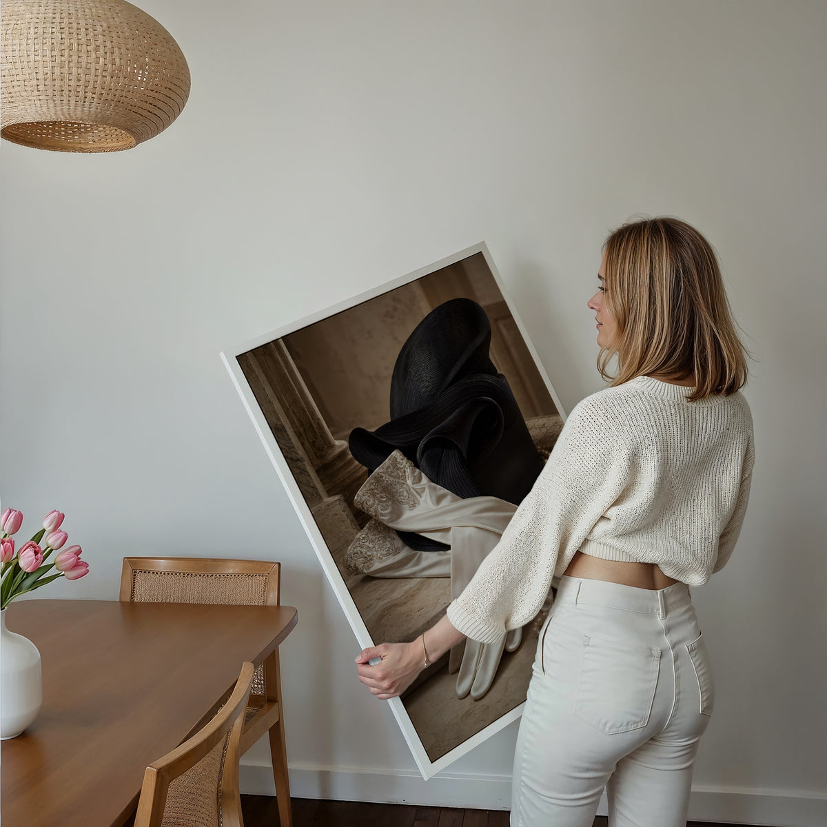 Motiv mit einem Paar weißer Satinhandschuhe neben einem schwarzen Hut und Perlenketten, über einem Bett im hellen Schlafzimmer.