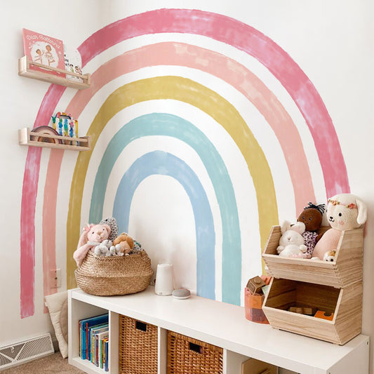 Verspielter Regenbogen Wandtattoo von justgoodmood in einem Kinderzimmer, das mit Spielzeug und Kuscheltieren dekoriert ist. Ideal für eine kreative und bunte Gestaltung.
